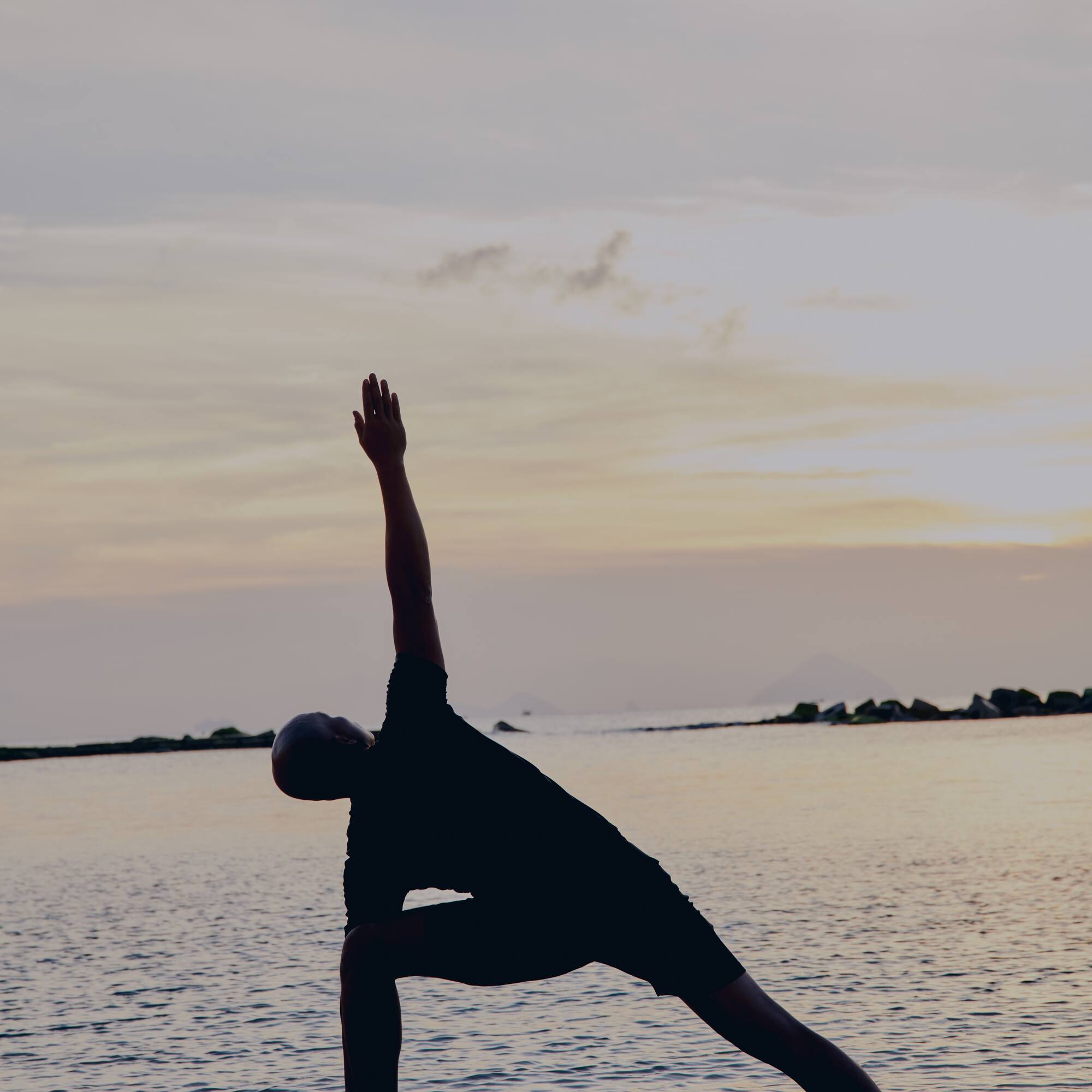 a man doing yoga on a beach