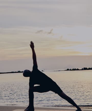 a man doing yoga on a beach
