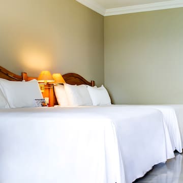a bed with white sheets and lamps
