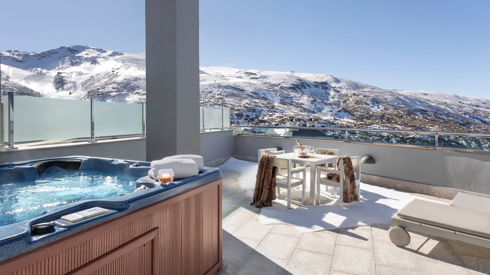 a hot tub on a rooftop with snow covered mountains in the background