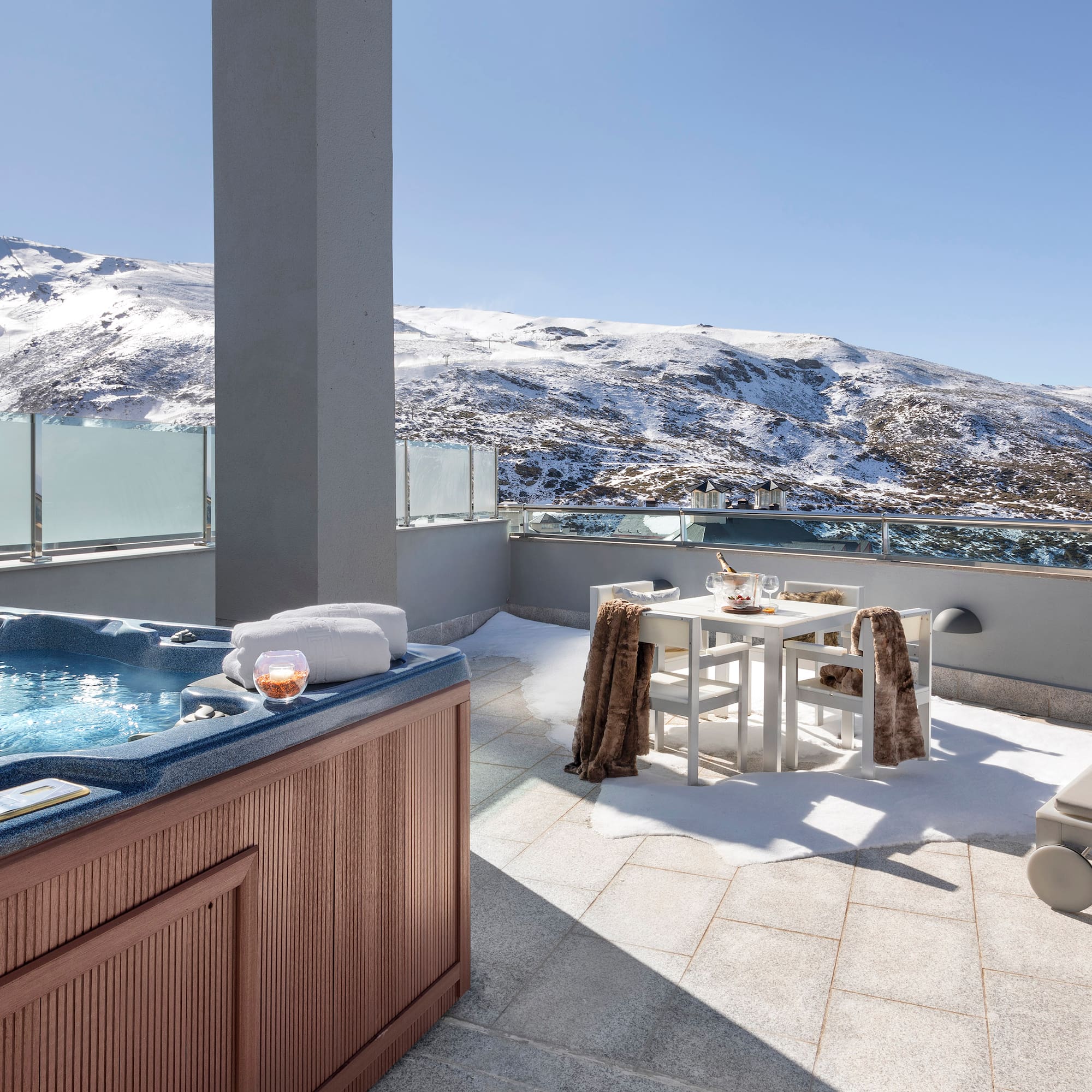 a hot tub on a rooftop with snow covered mountains in the background