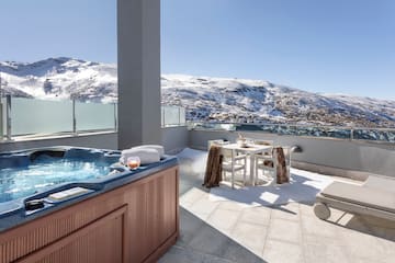 a hot tub on a rooftop with snow covered mountains in the background