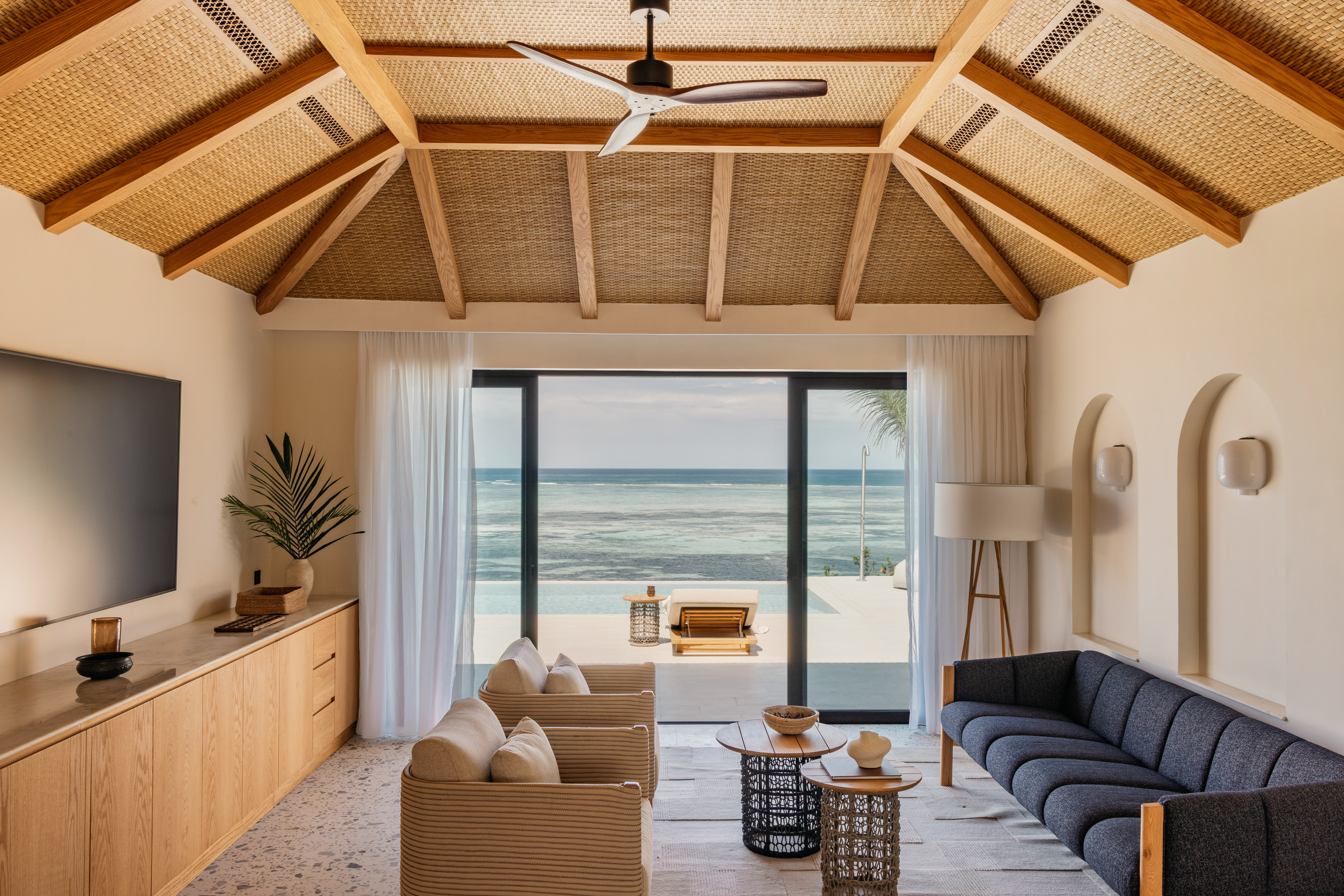 Coastal living room with ocean views, rattan ceiling, and modern furnishings.