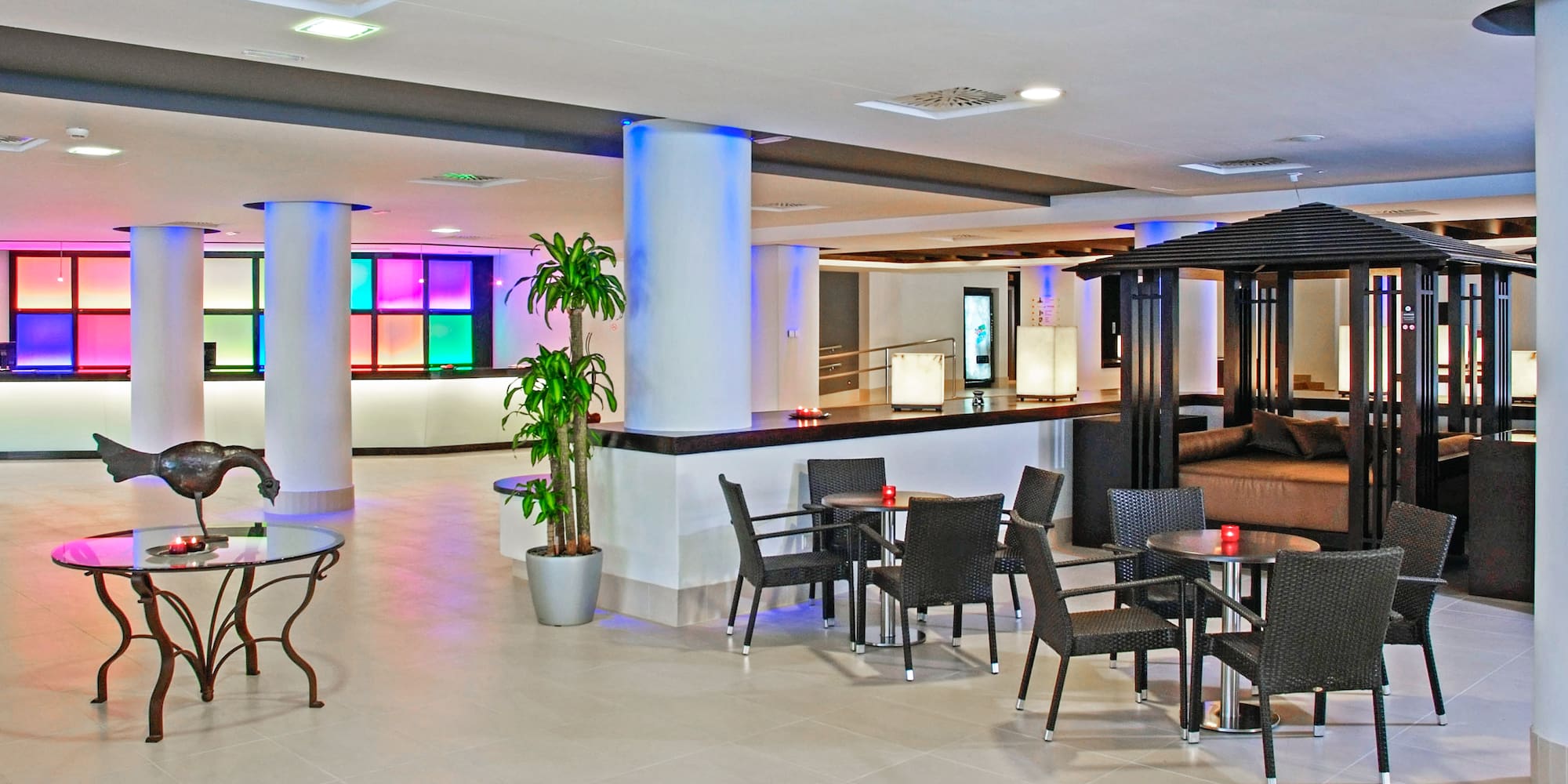 Modern hotel lobby lounge with colorful LED lighting, reception, and diverse seating.