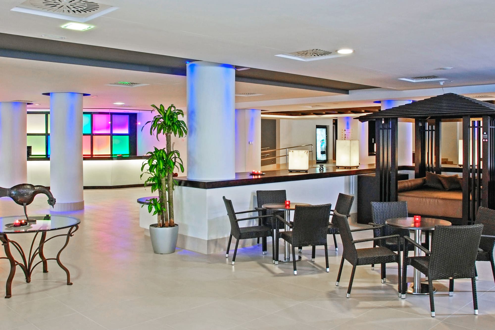 Modern hotel lobby lounge with colorful LED lighting, reception, and diverse seating.