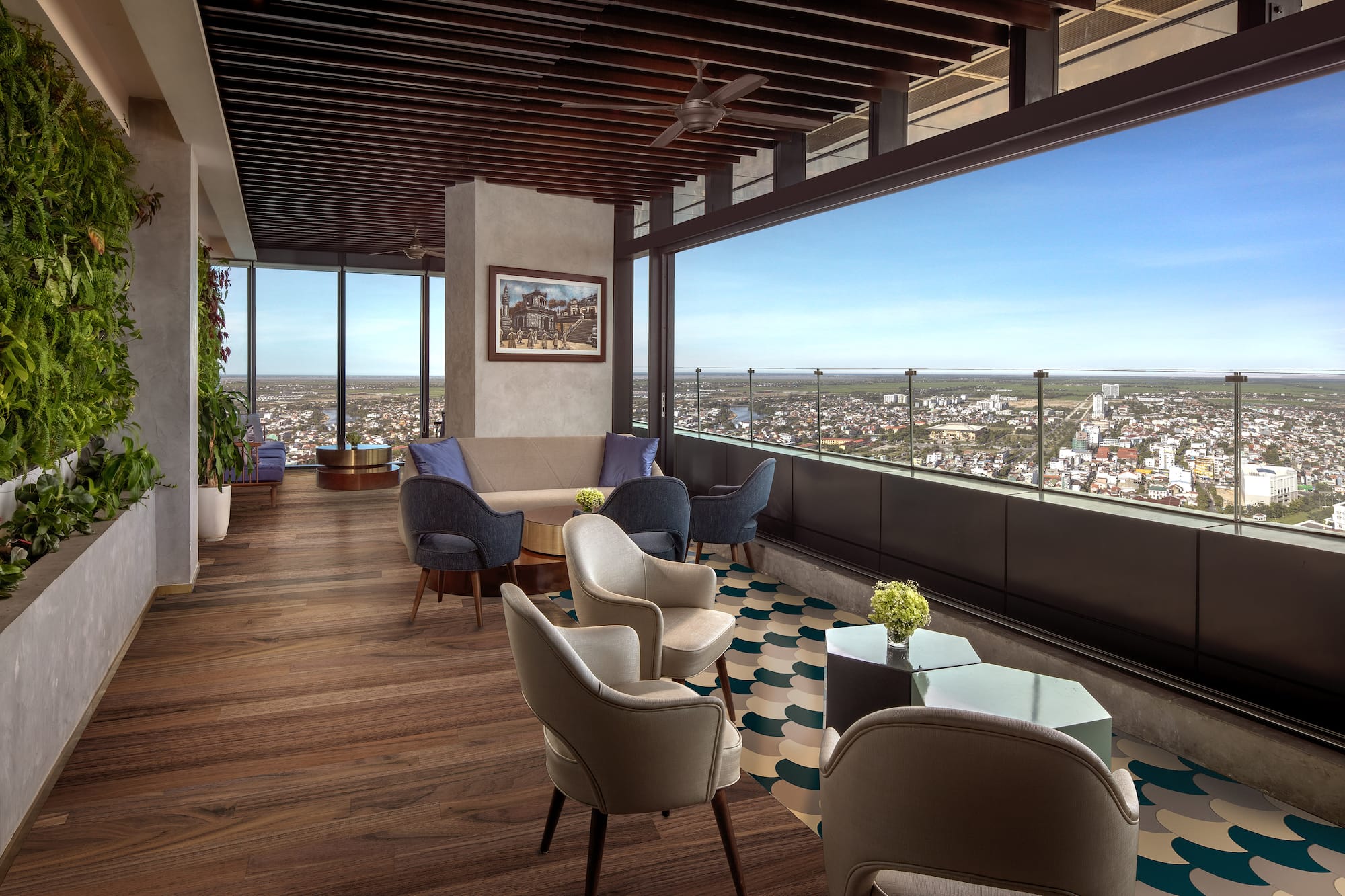 High-rise lounge with panoramic city view, green wall, and modern seating.
