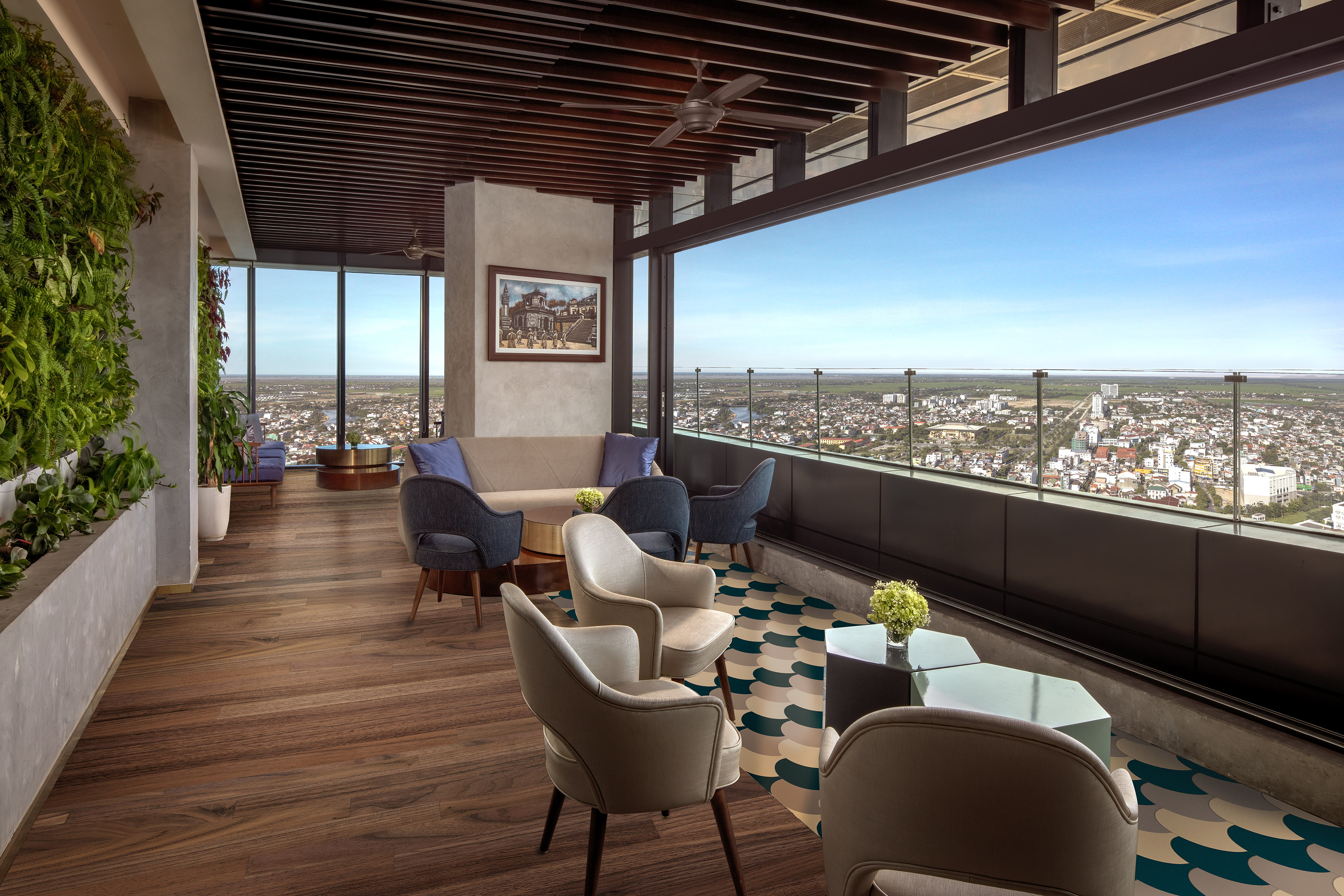 High-rise lounge with panoramic city view, green wall, and modern seating.