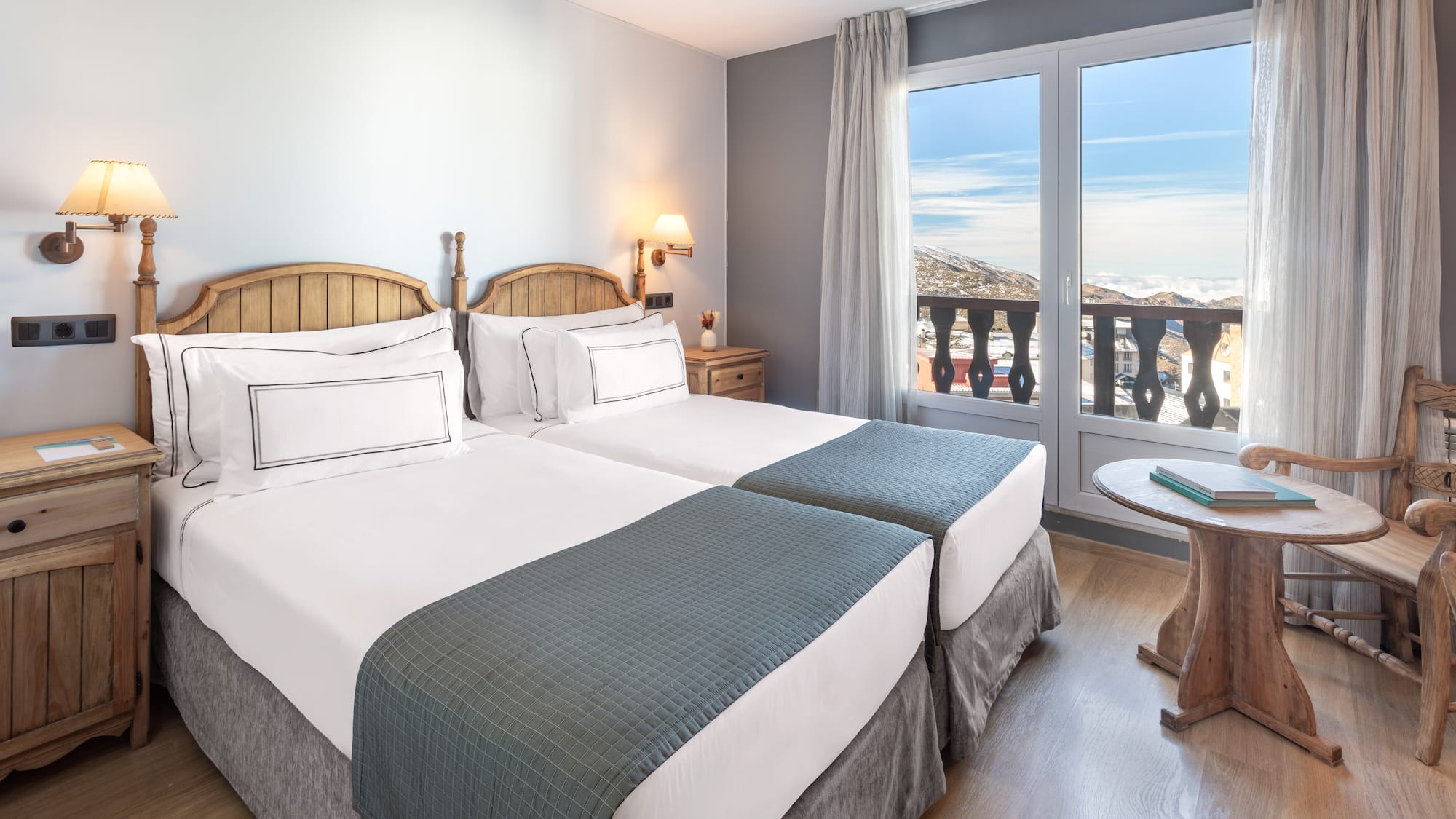 a room with two beds and a table with a balcony