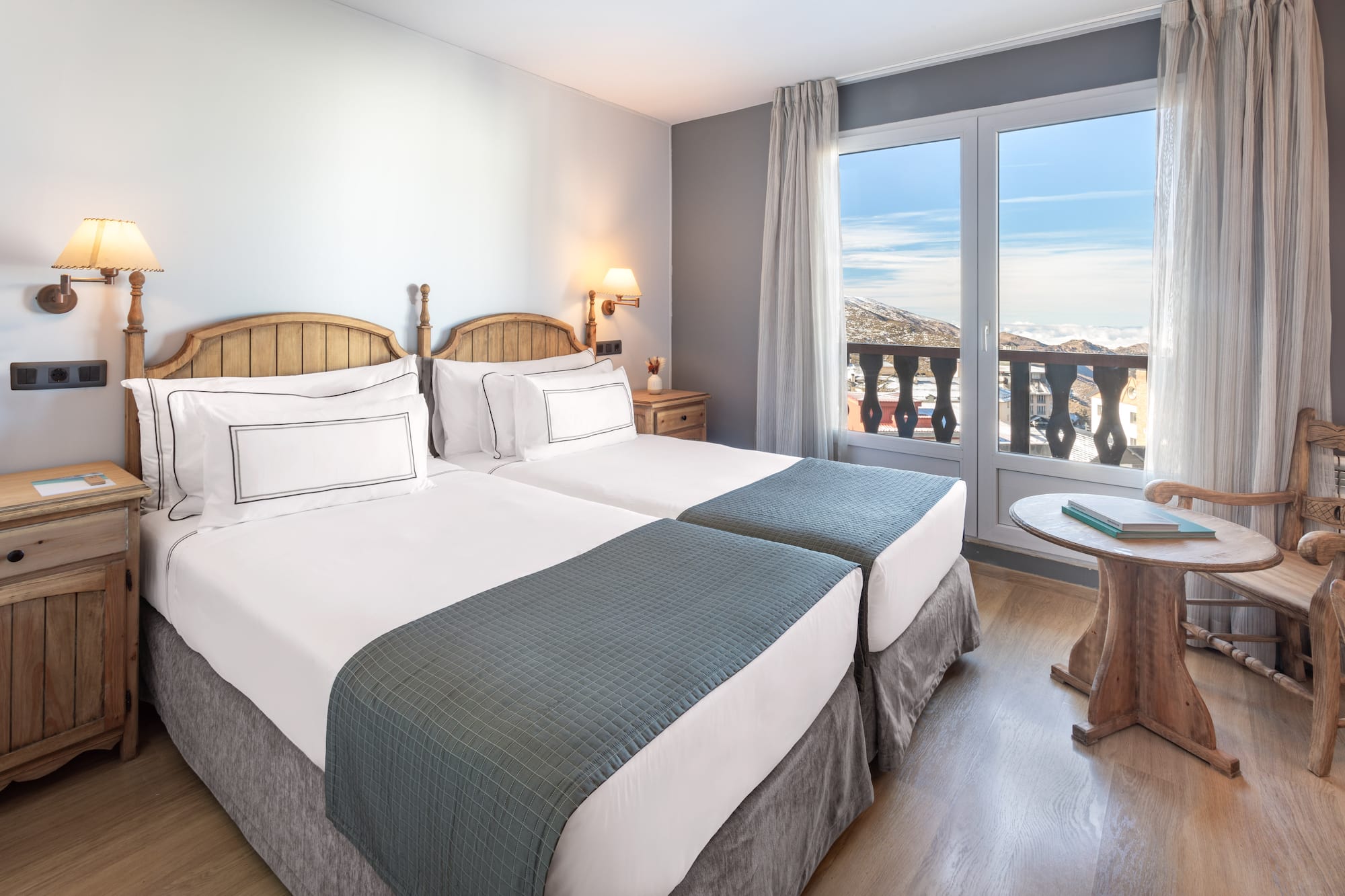 a room with two beds and a table with a balcony