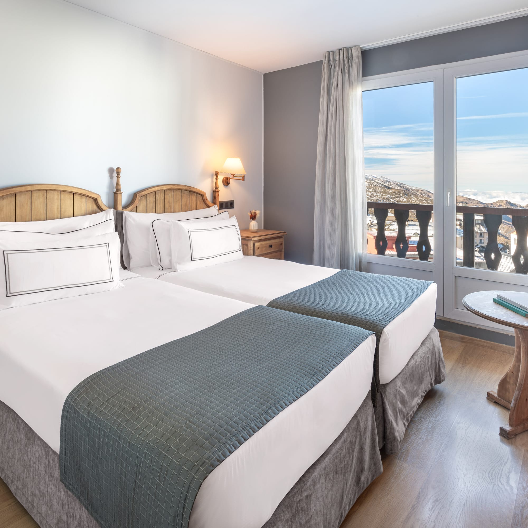 a room with two beds and a table with a balcony