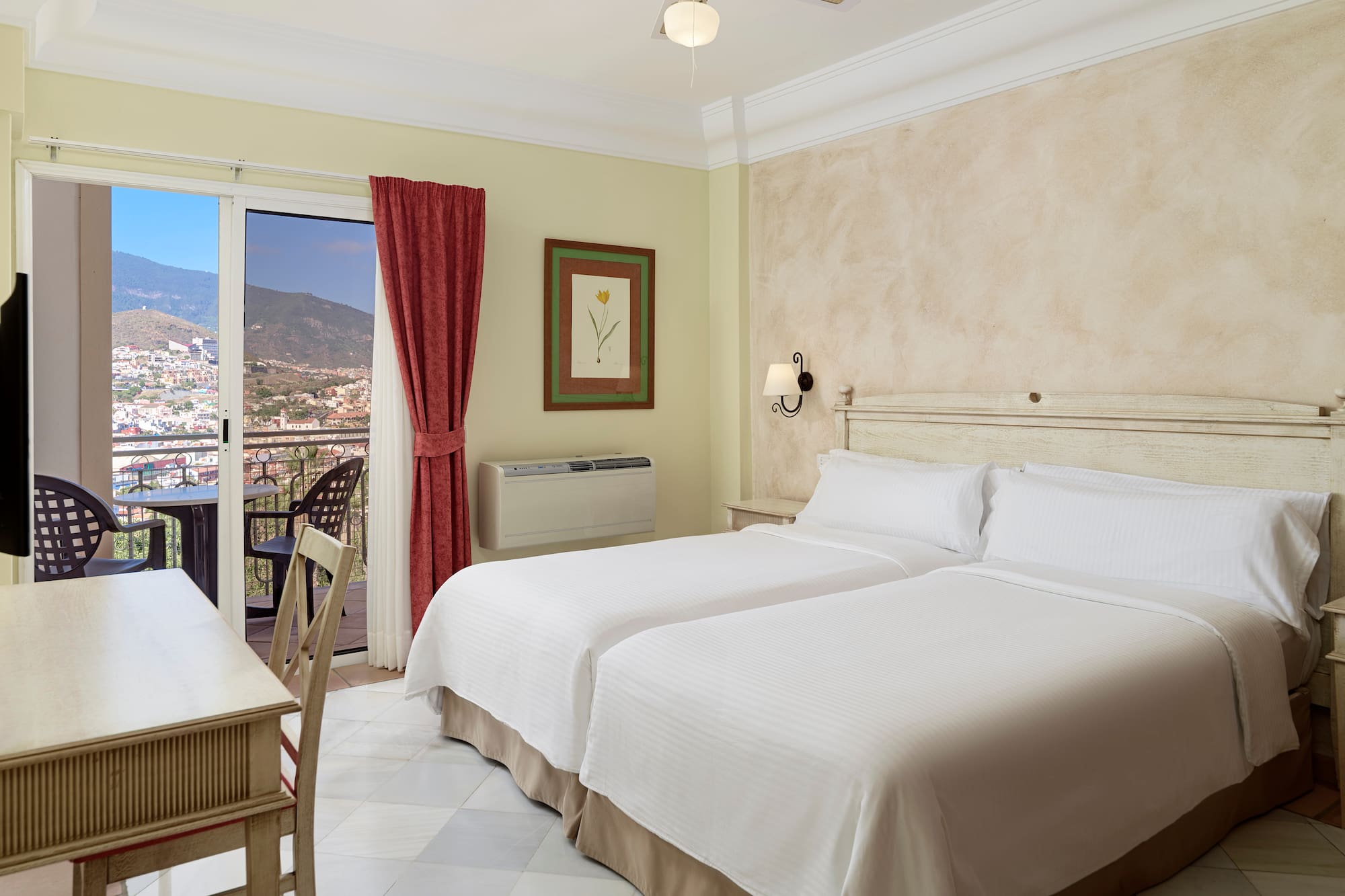 a room with two beds and a table and a balcony