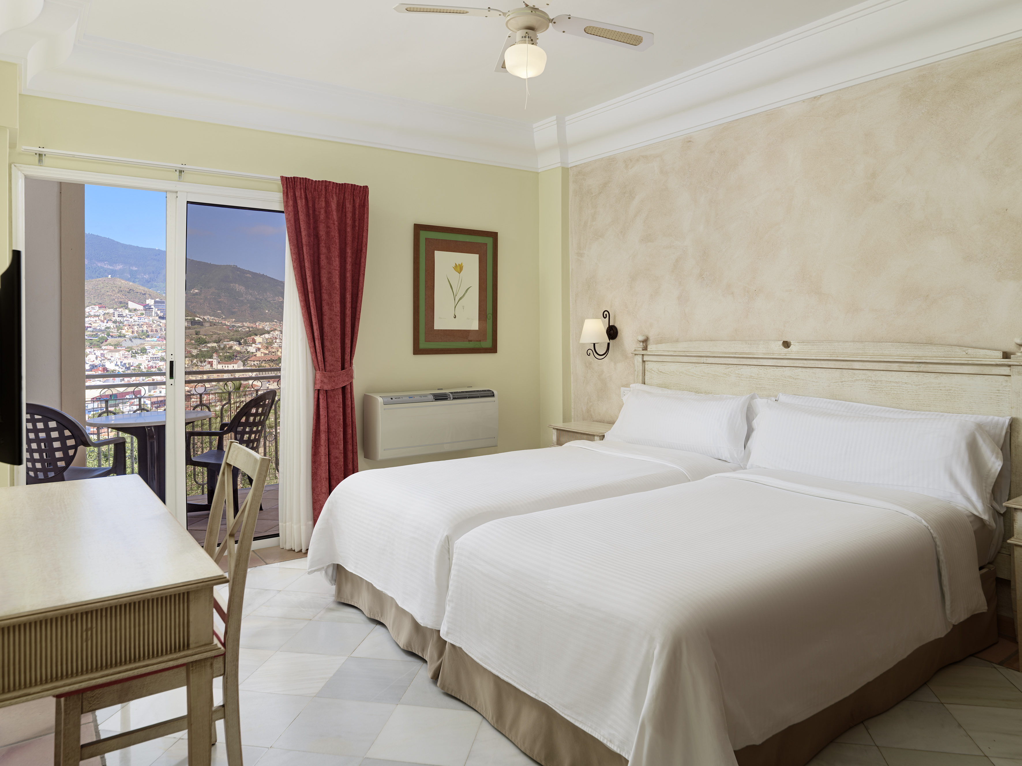 Hotel room with twin beds, private balcony featuring mountain and city view.
