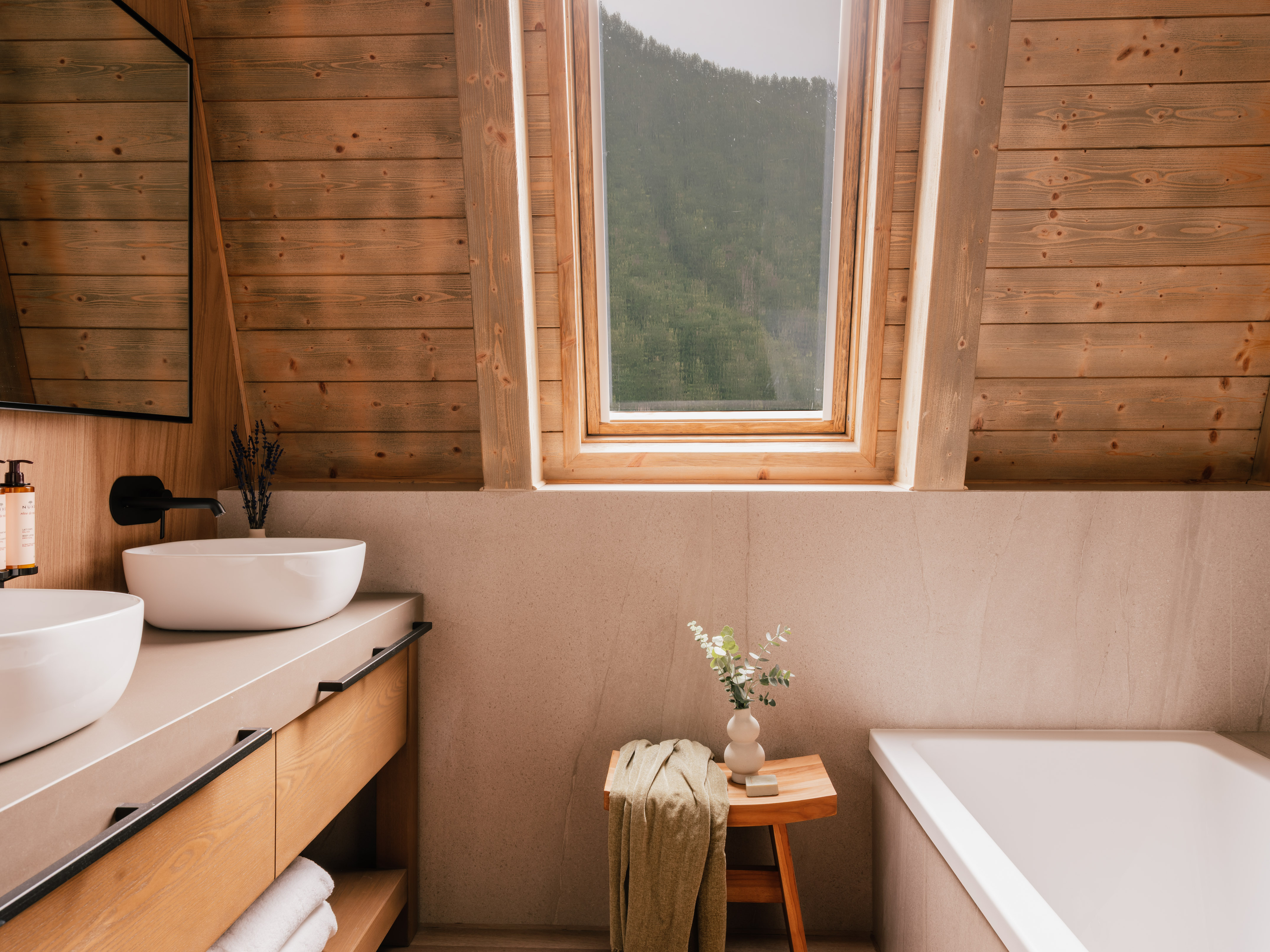 Wood-paneled attic bathroom with skylight, double vanity, and bathtub.