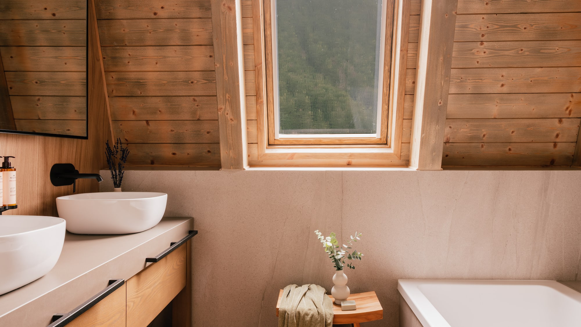 Wood-paneled attic bathroom with skylight, double vanity, and bathtub.