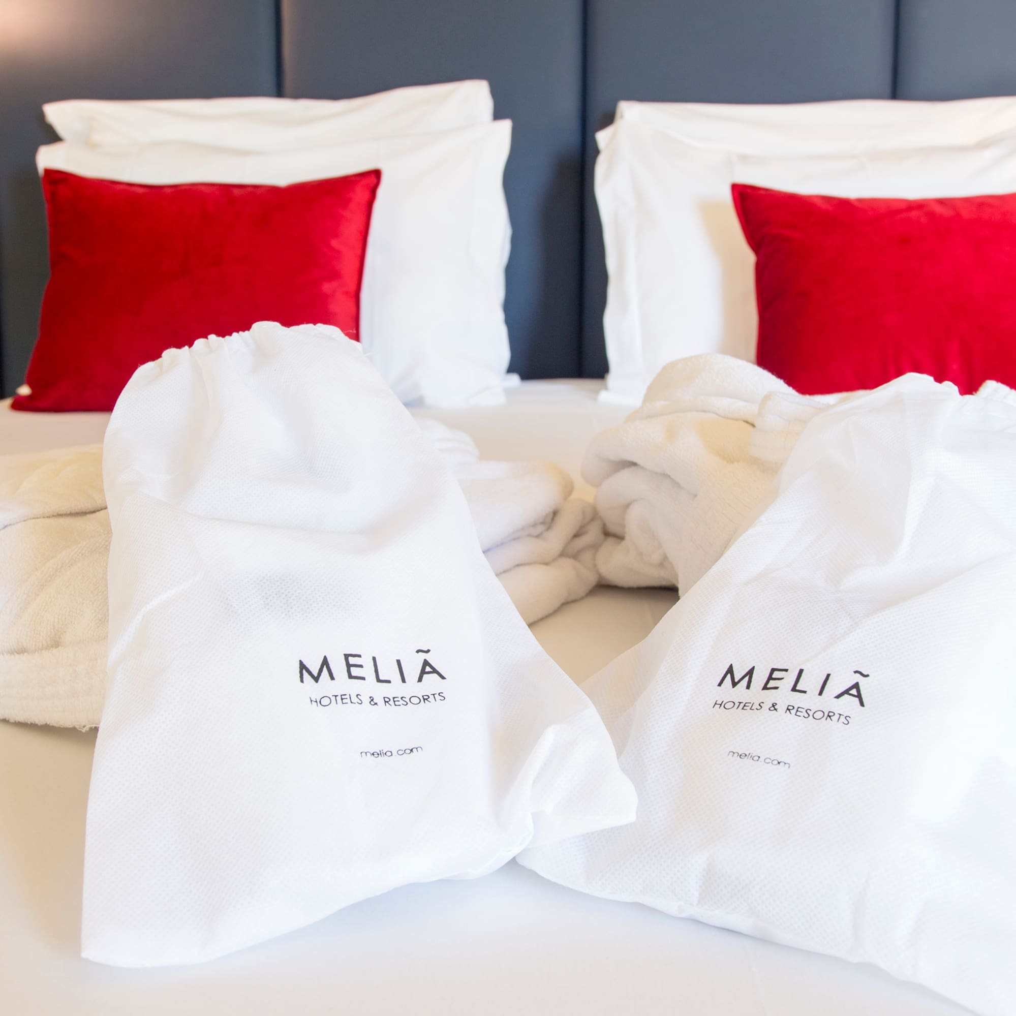 a bed with white towels and red pillows