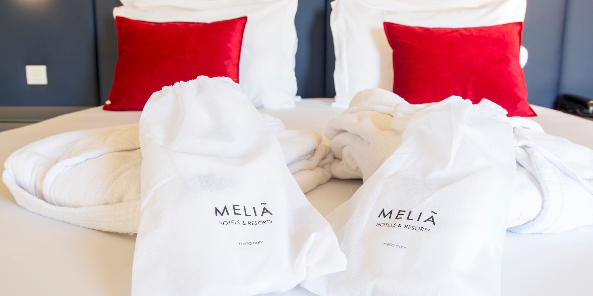 a bed with white towels and red pillows