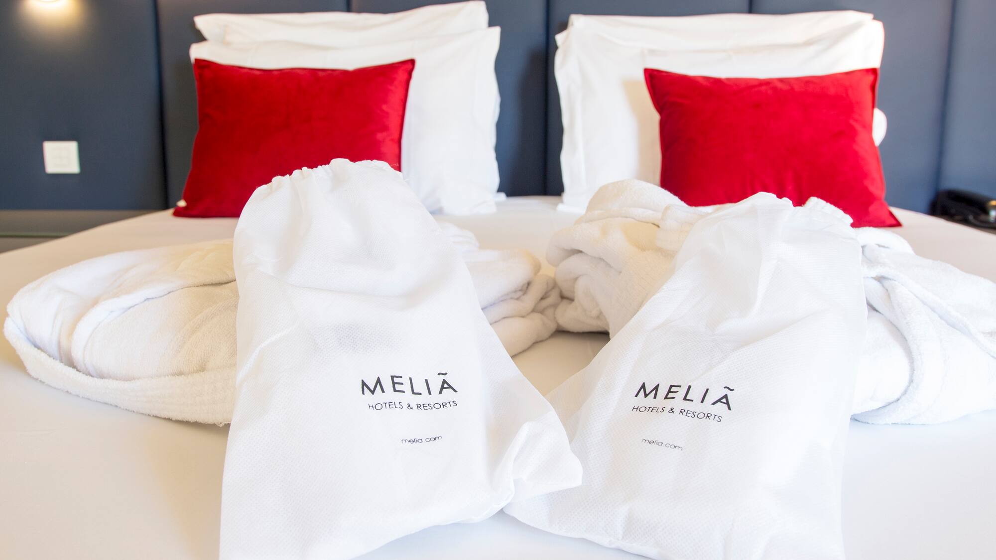 a bed with white towels and red pillows