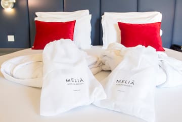 a bed with white towels and red pillows