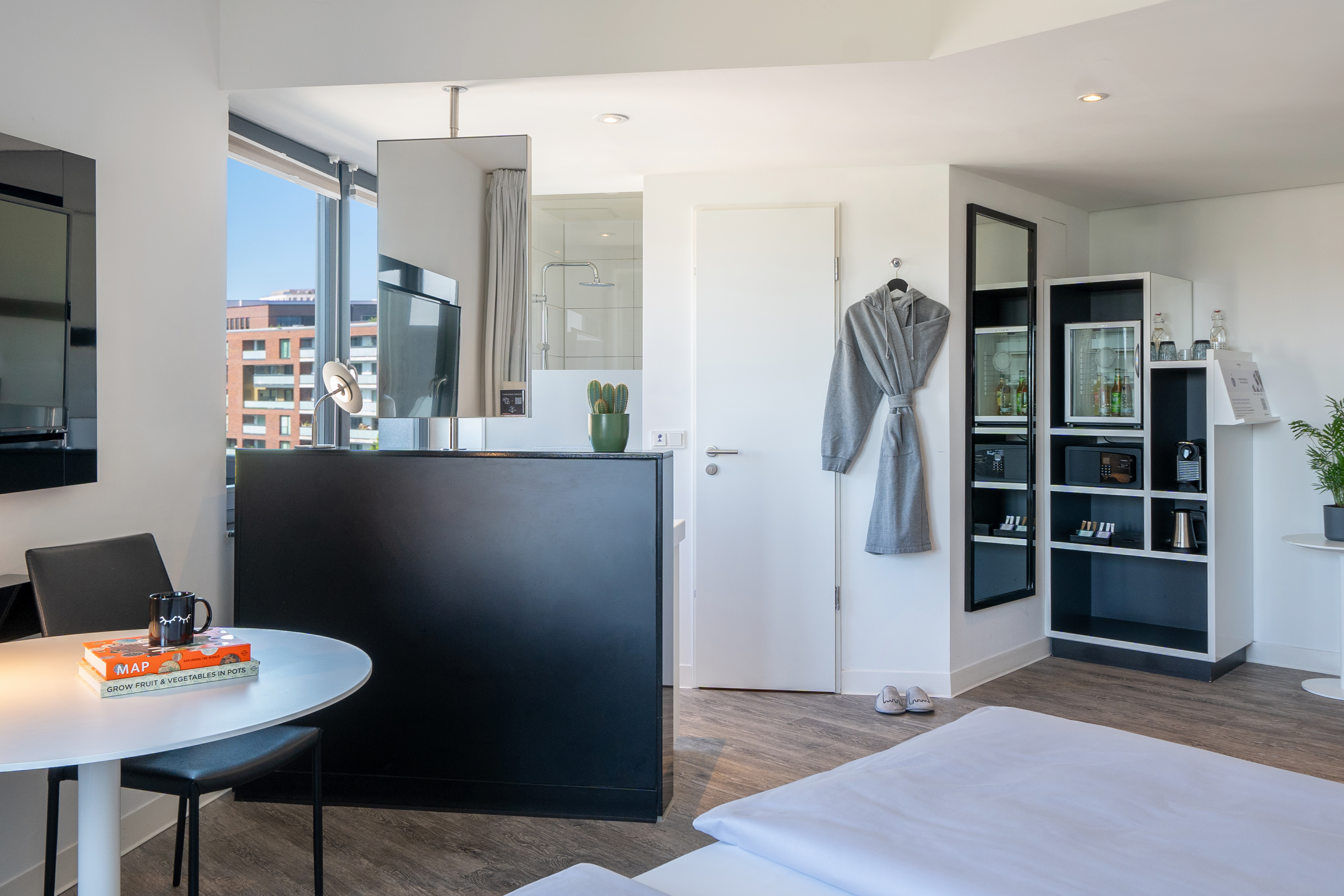 Modern hotel studio with bed, dining, city view, and compact minibar.