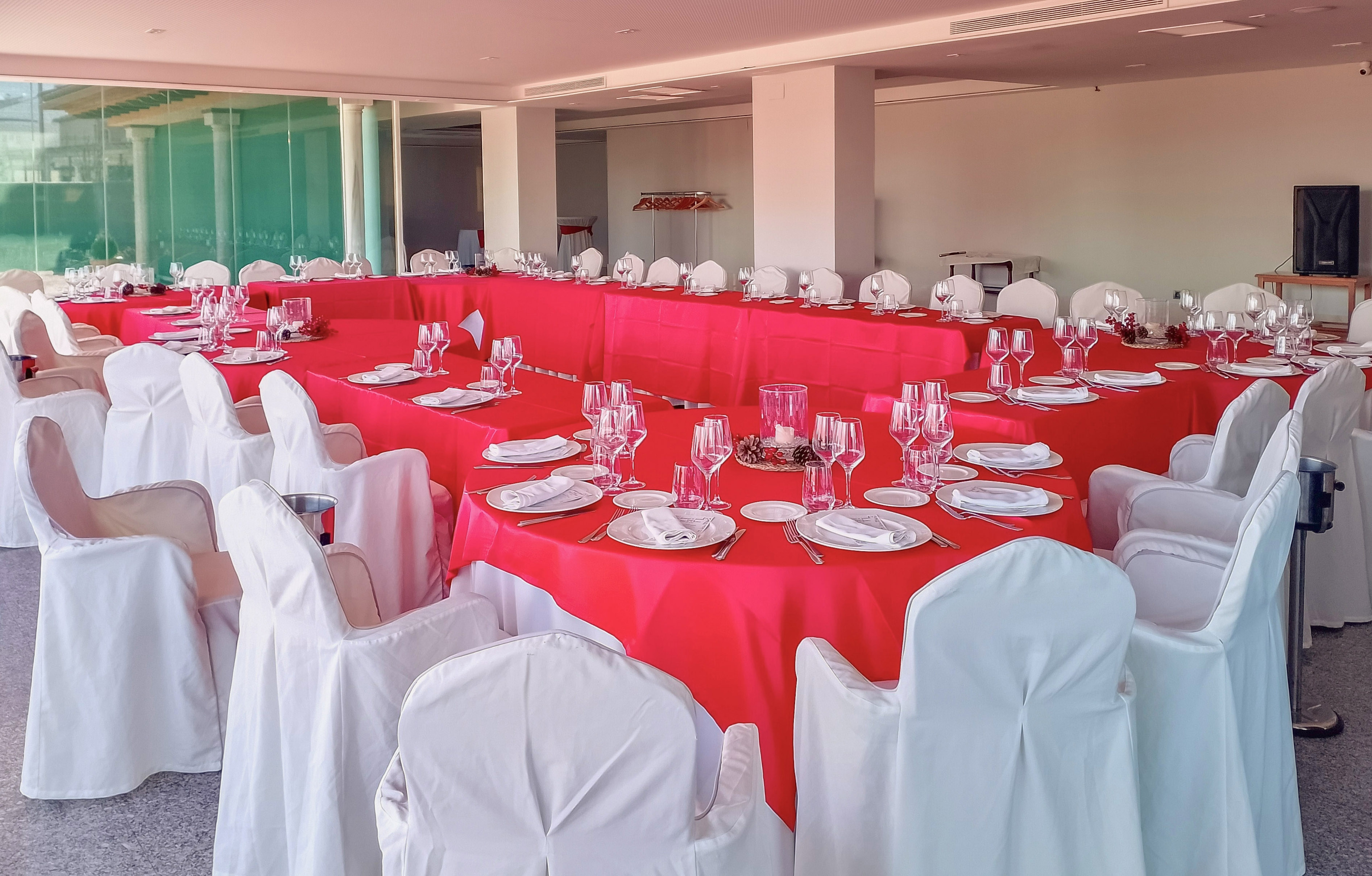 U-shaped banquet table with red tablecloths, white chairs, and elegant place settings.