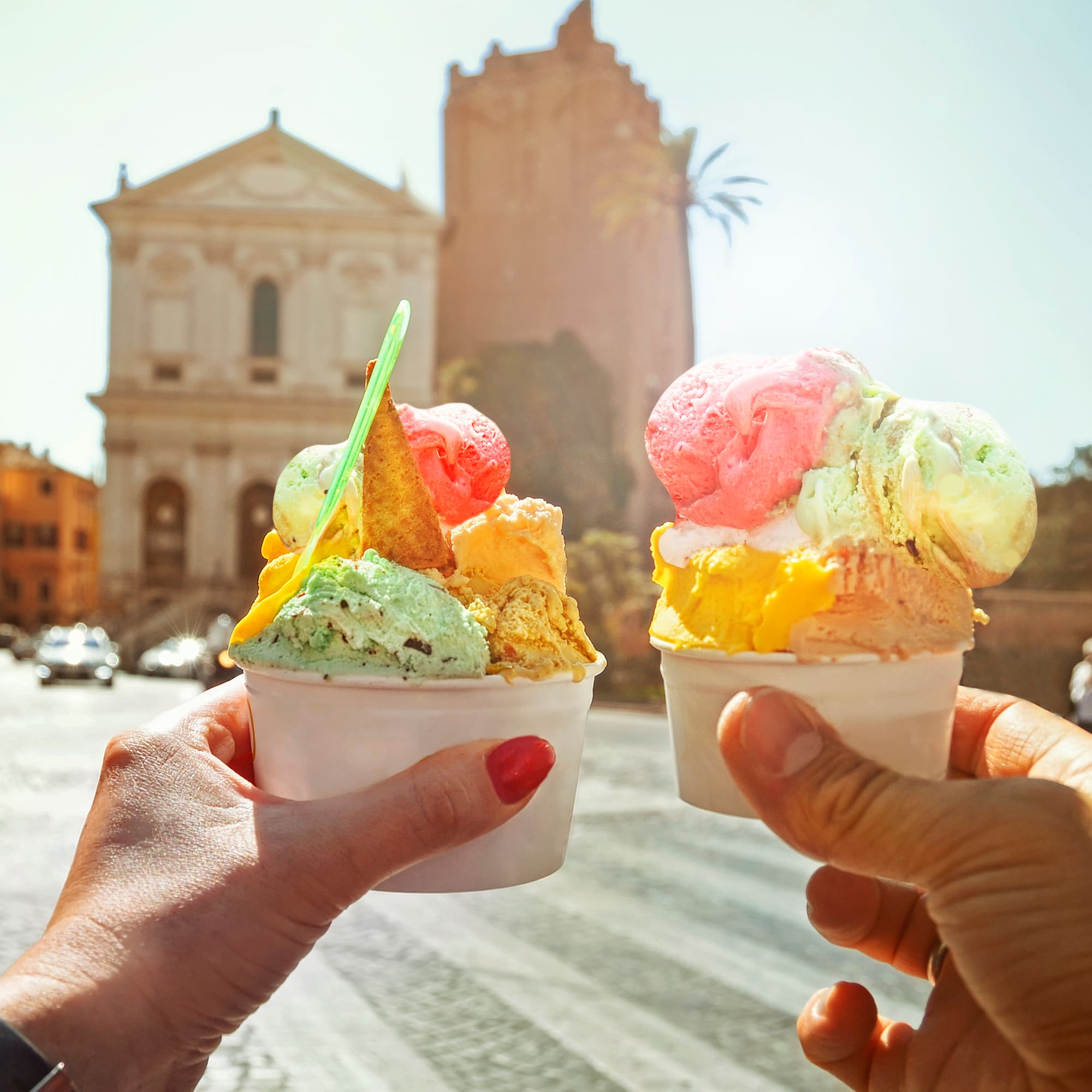 two hands holding two cups of ice cream