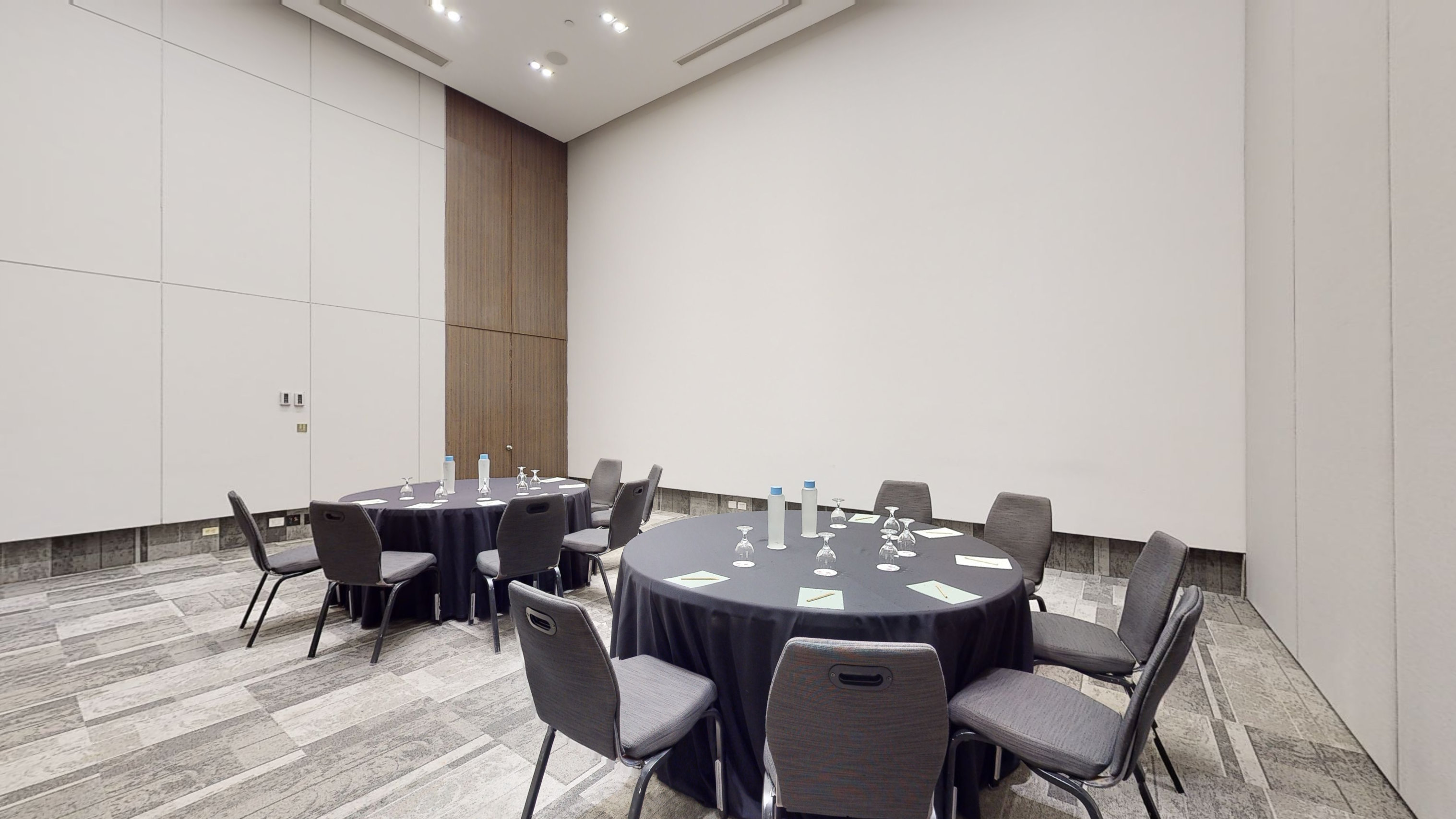 Modern conference room with round tables, chairs, water bottles, and notepads.