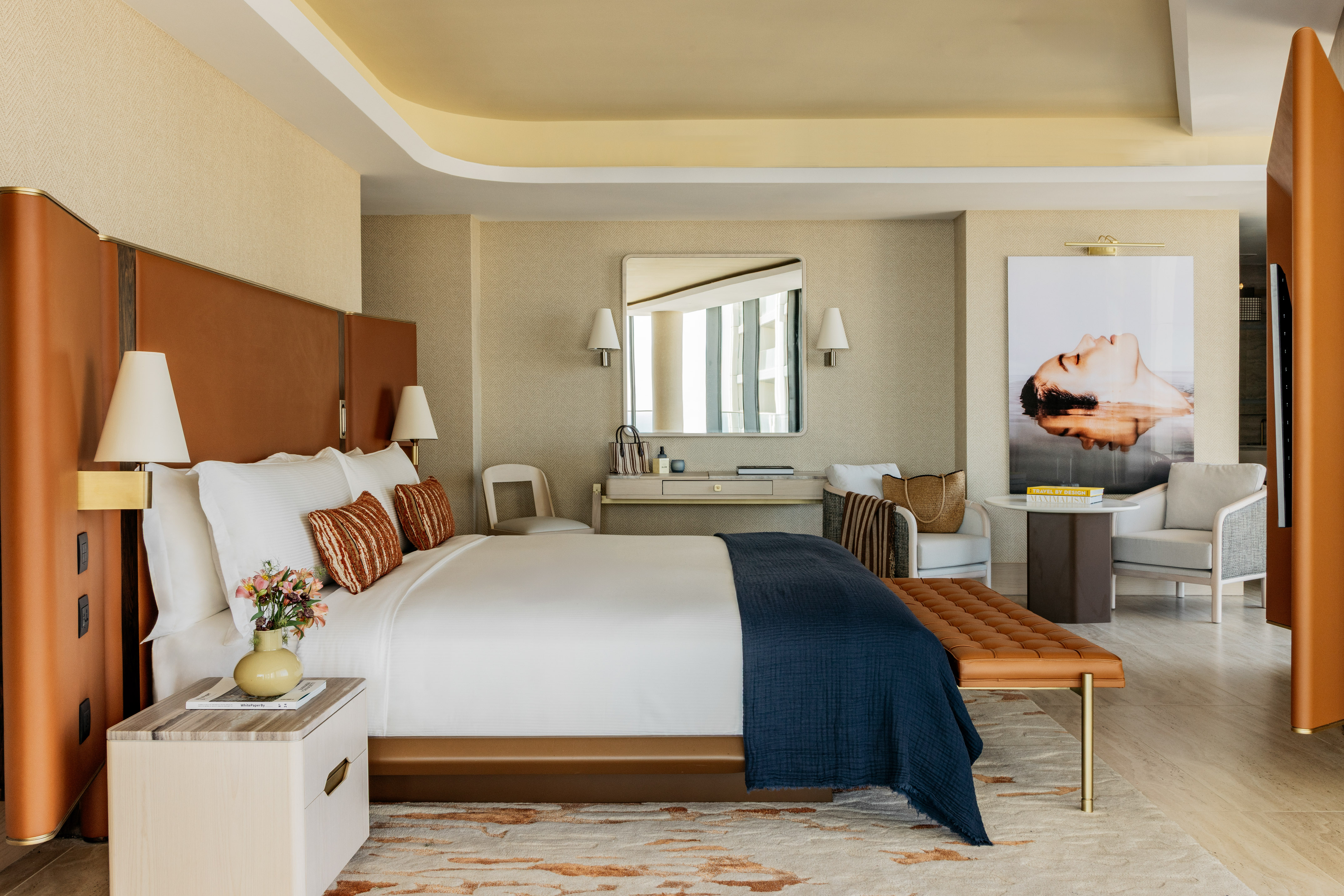 Luxury hotel bedroom with king bed, brown headboard, and modern decor.