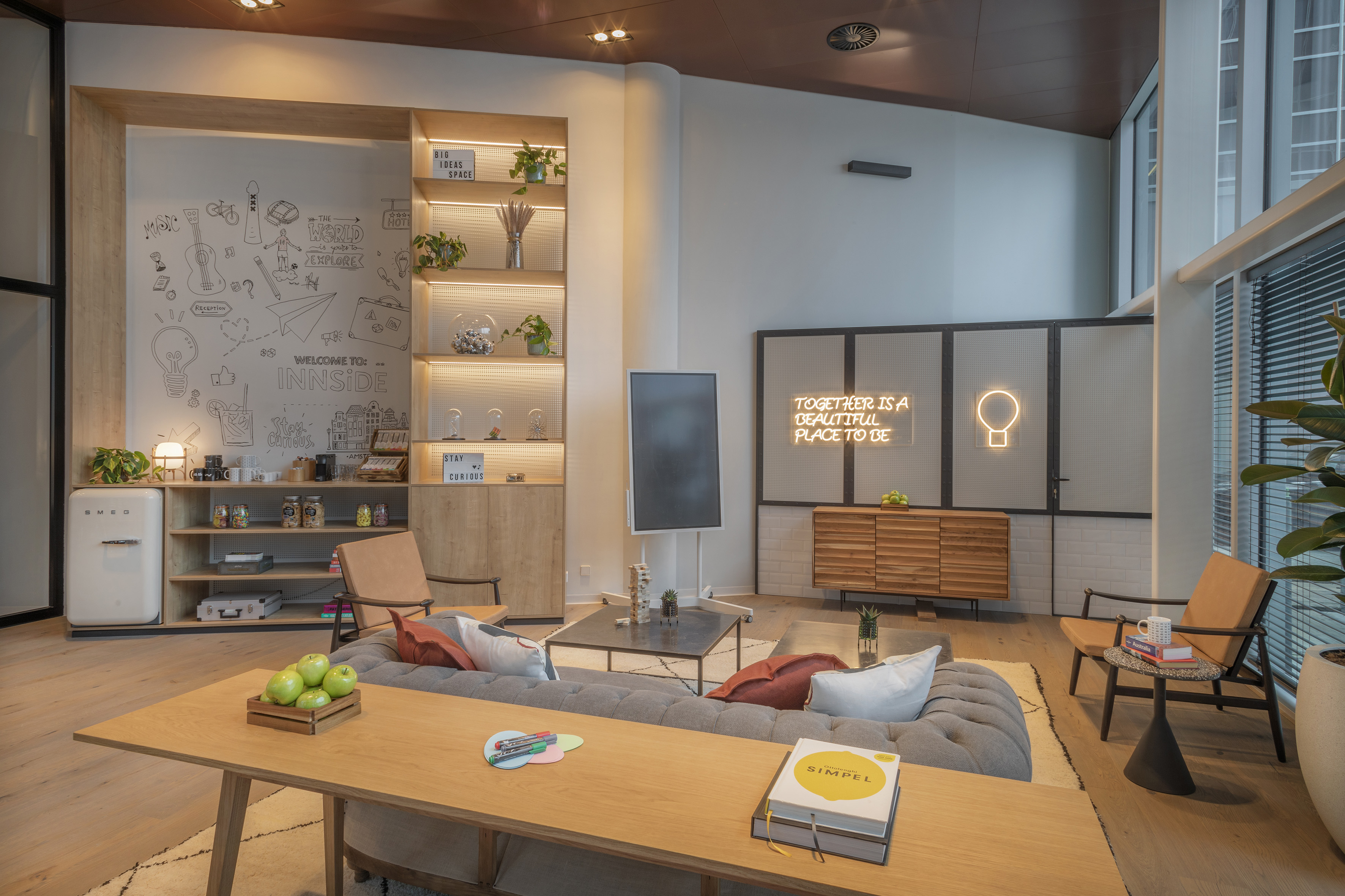 Modern hotel lounge with wall mural, neon sign, and comfortable sofa seating.