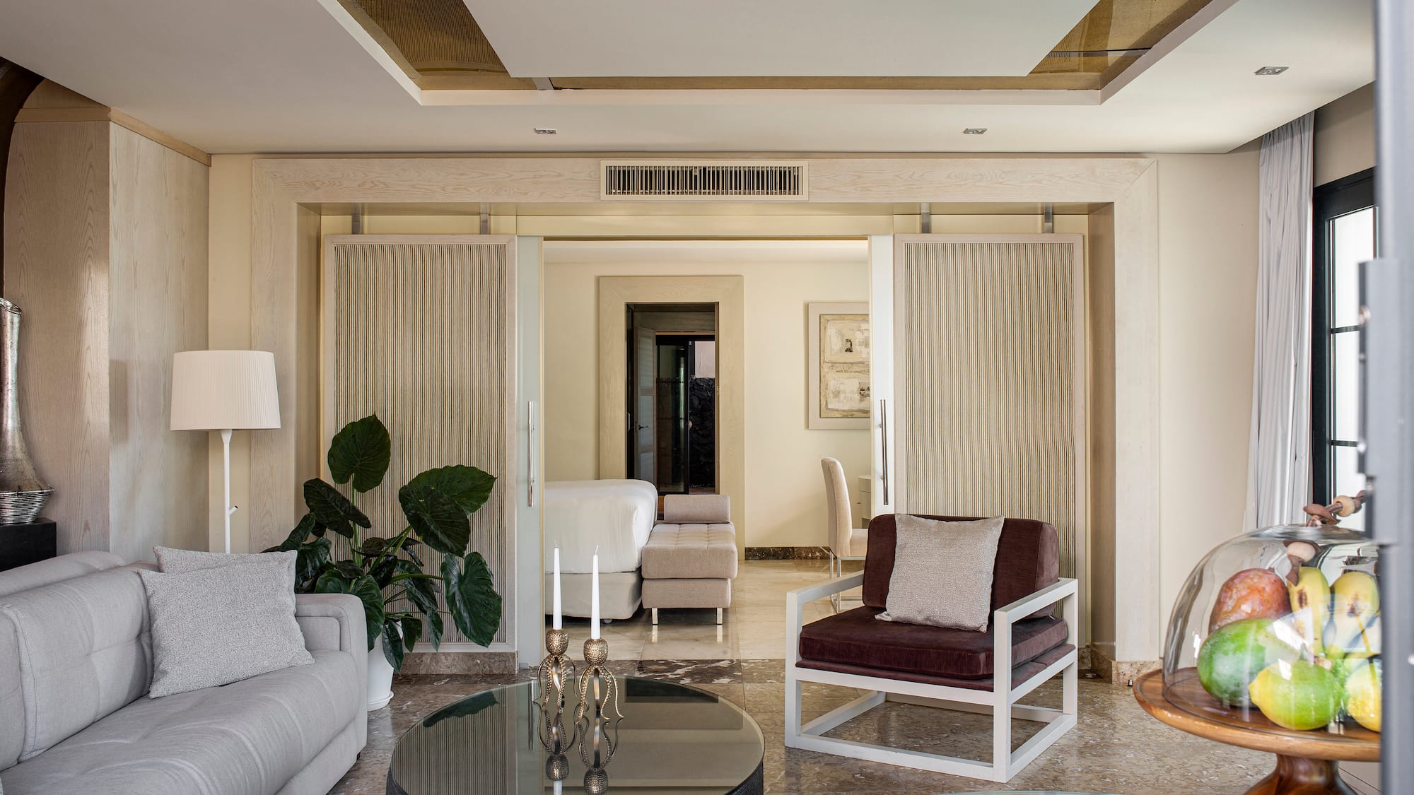 Sala de estar moderna y elegante con sofá, sillón, mesa de cristal y planta.