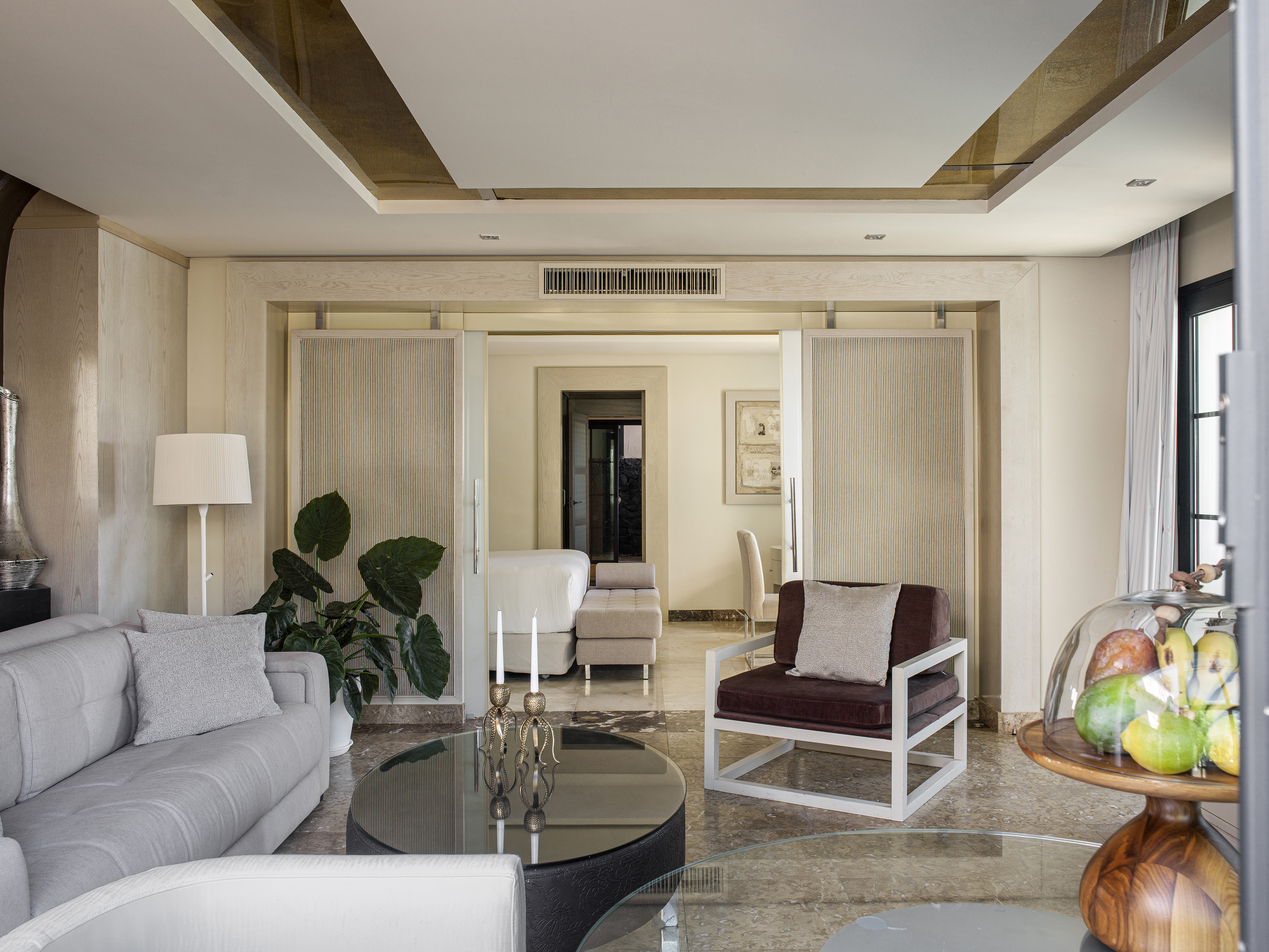 Sala de estar moderna y elegante con sofá, sillón, mesa de cristal y planta.