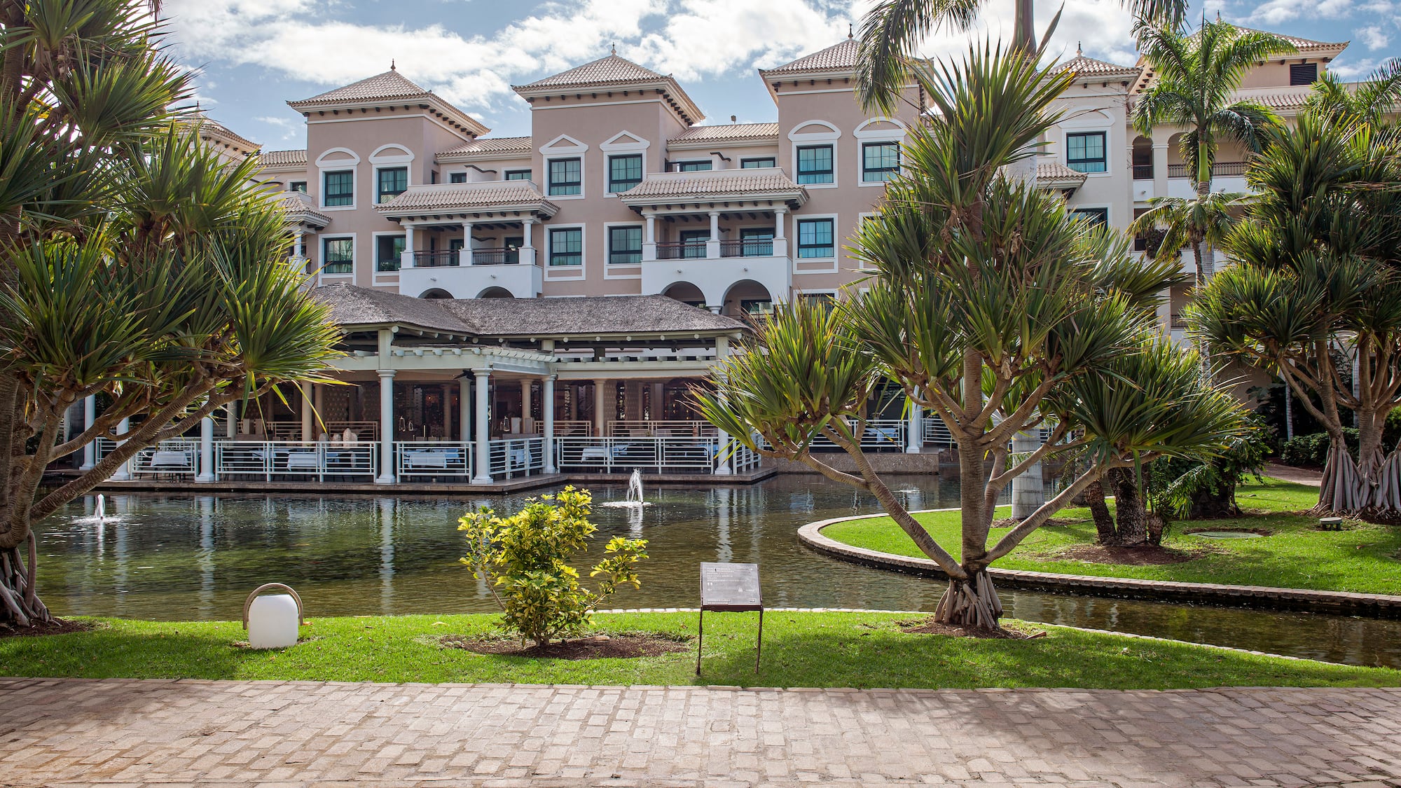Mediterranean resort with tropical gardens, reflective pond, and palm trees.