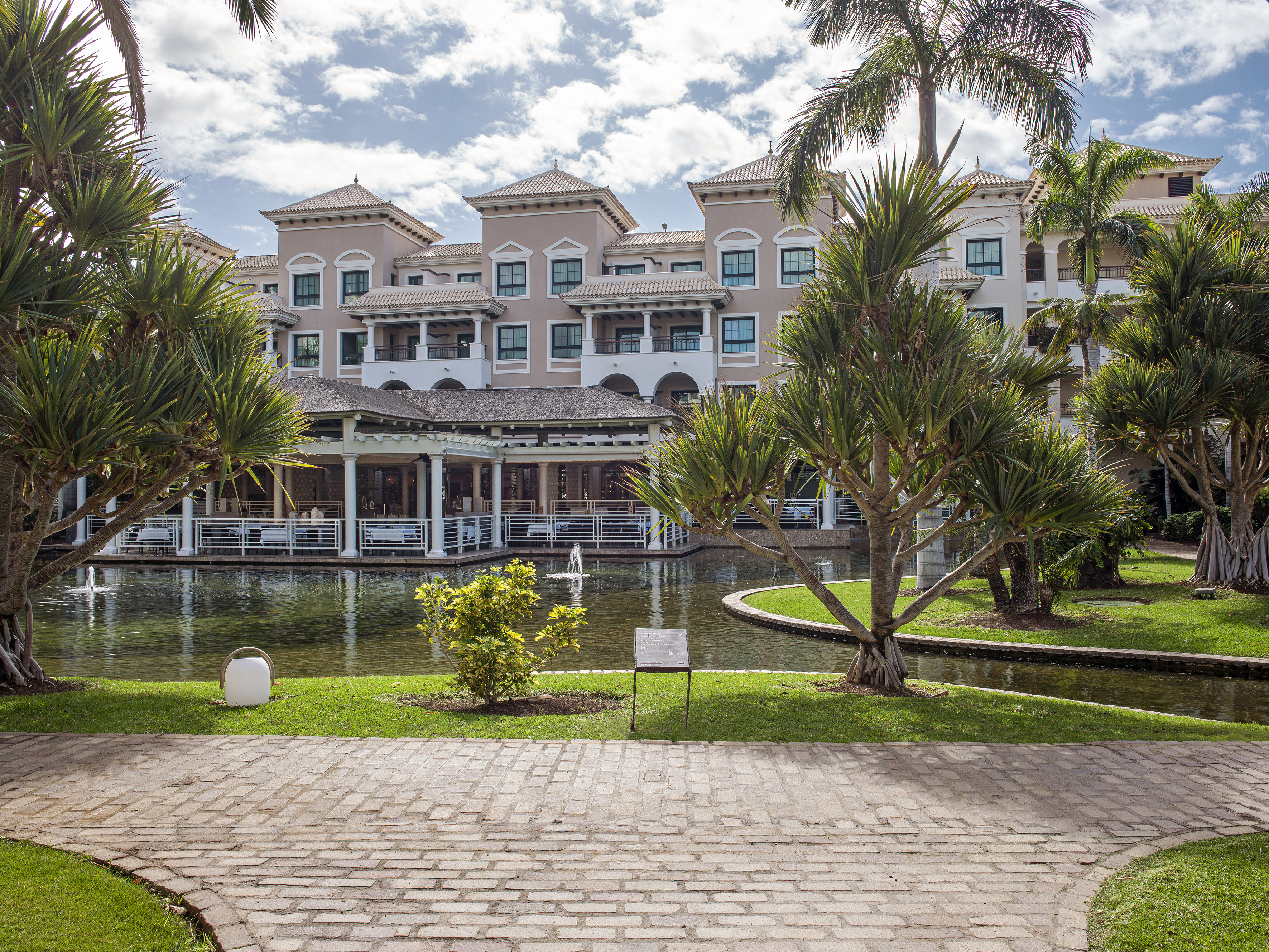 Mediterranean resort with tropical gardens, reflective pond, and palm trees.