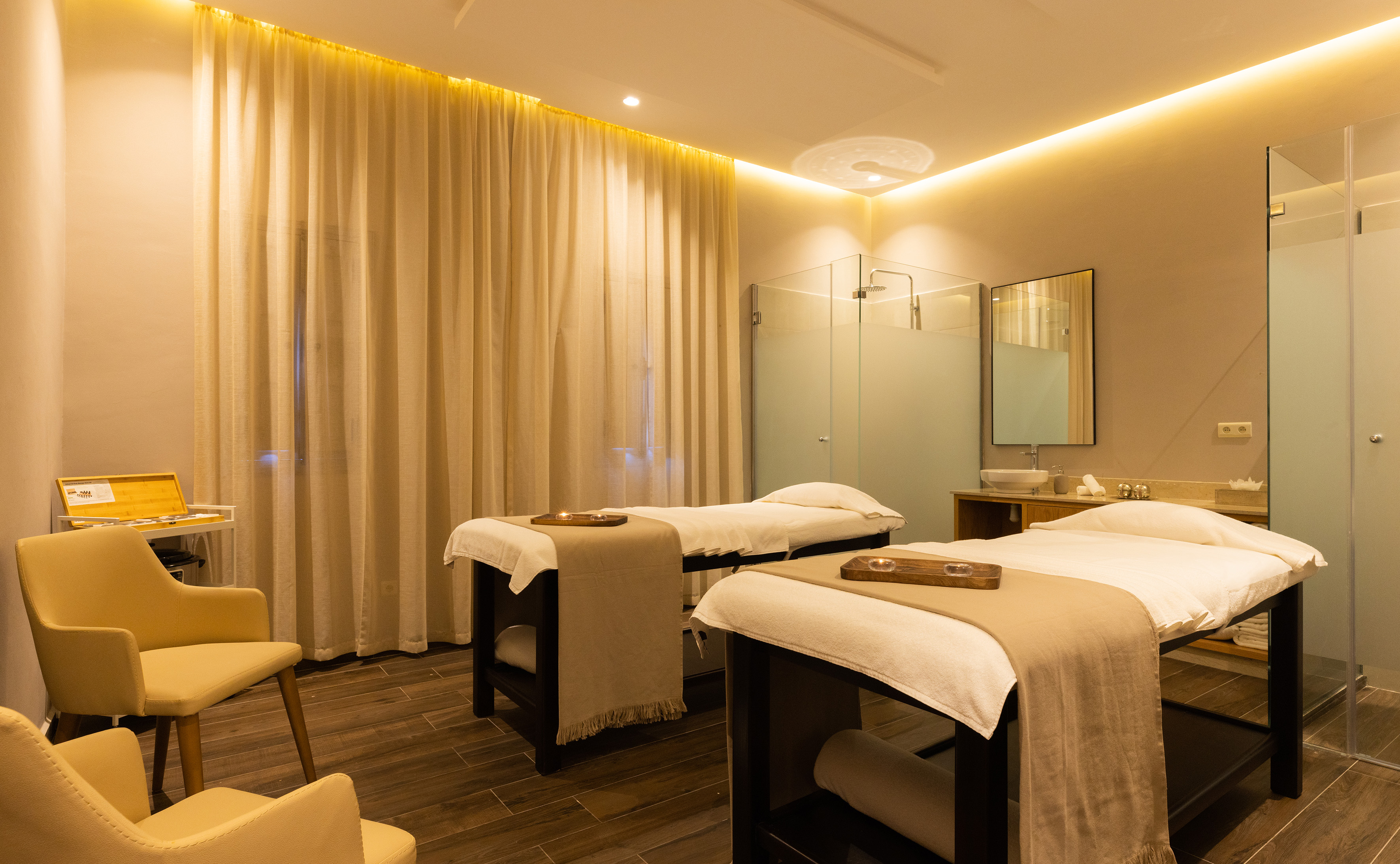 Luxurious spa treatment room with two massage beds and warm ambient lighting.