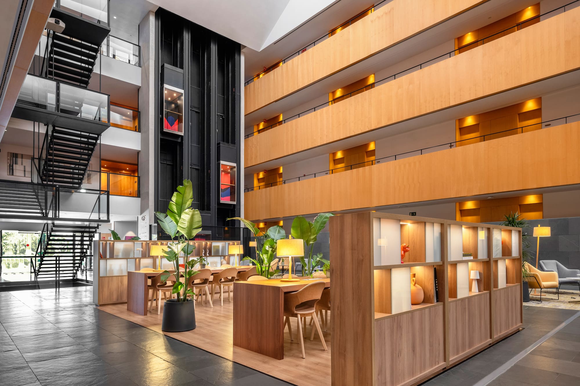Modern hotel lobby with inviting co-working space, wood, and glass elevators.
