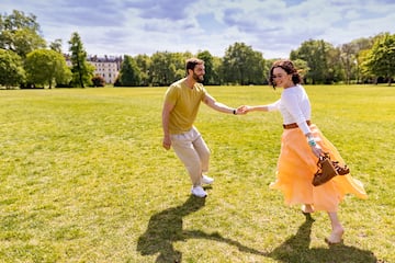 a man and woman holding hands and running in a field