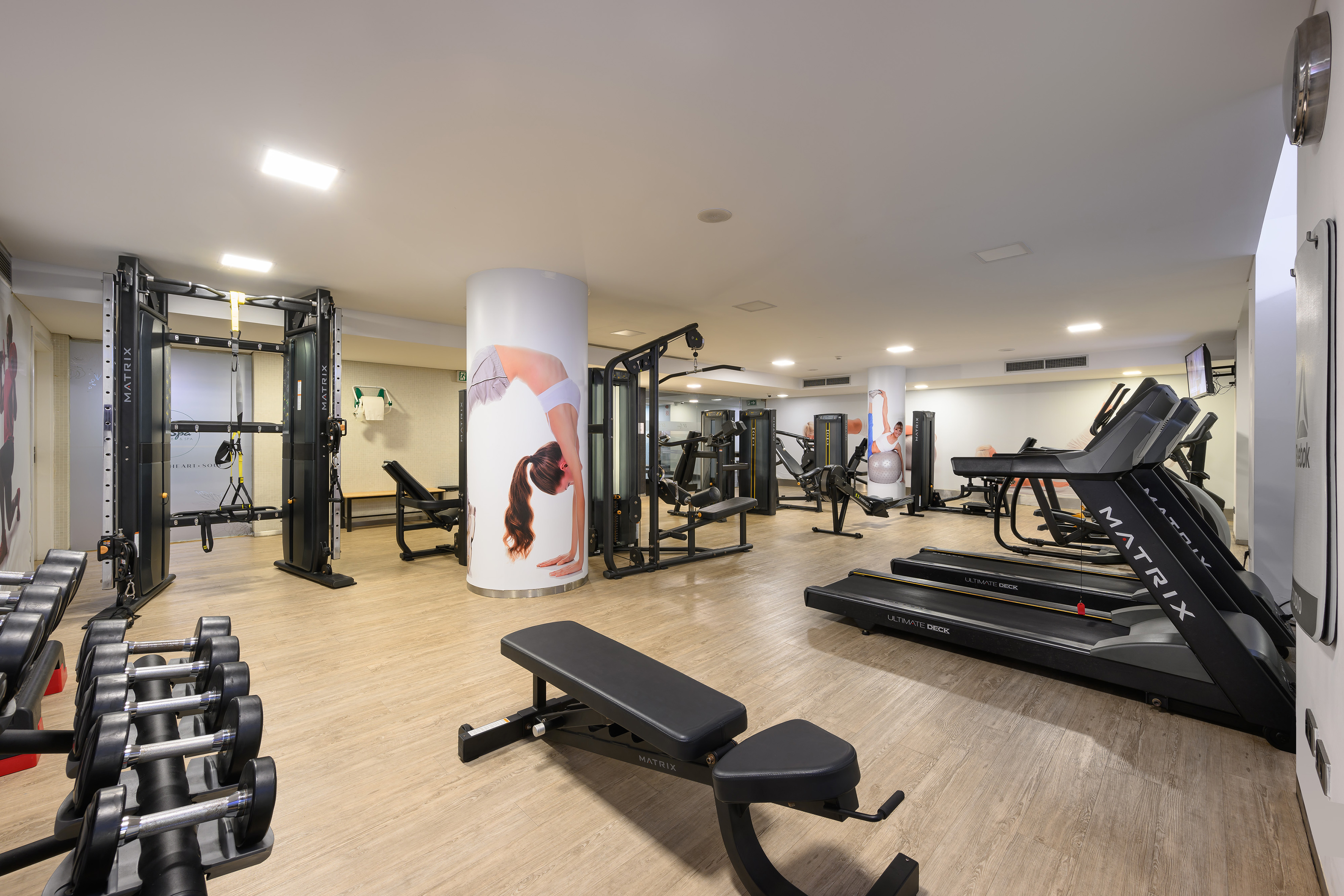 Hotel gym with Matrix treadmills, dumbbells, weight benches, and cable machines.