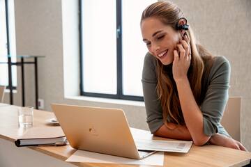 a woman wearing a headset and looking at a laptop