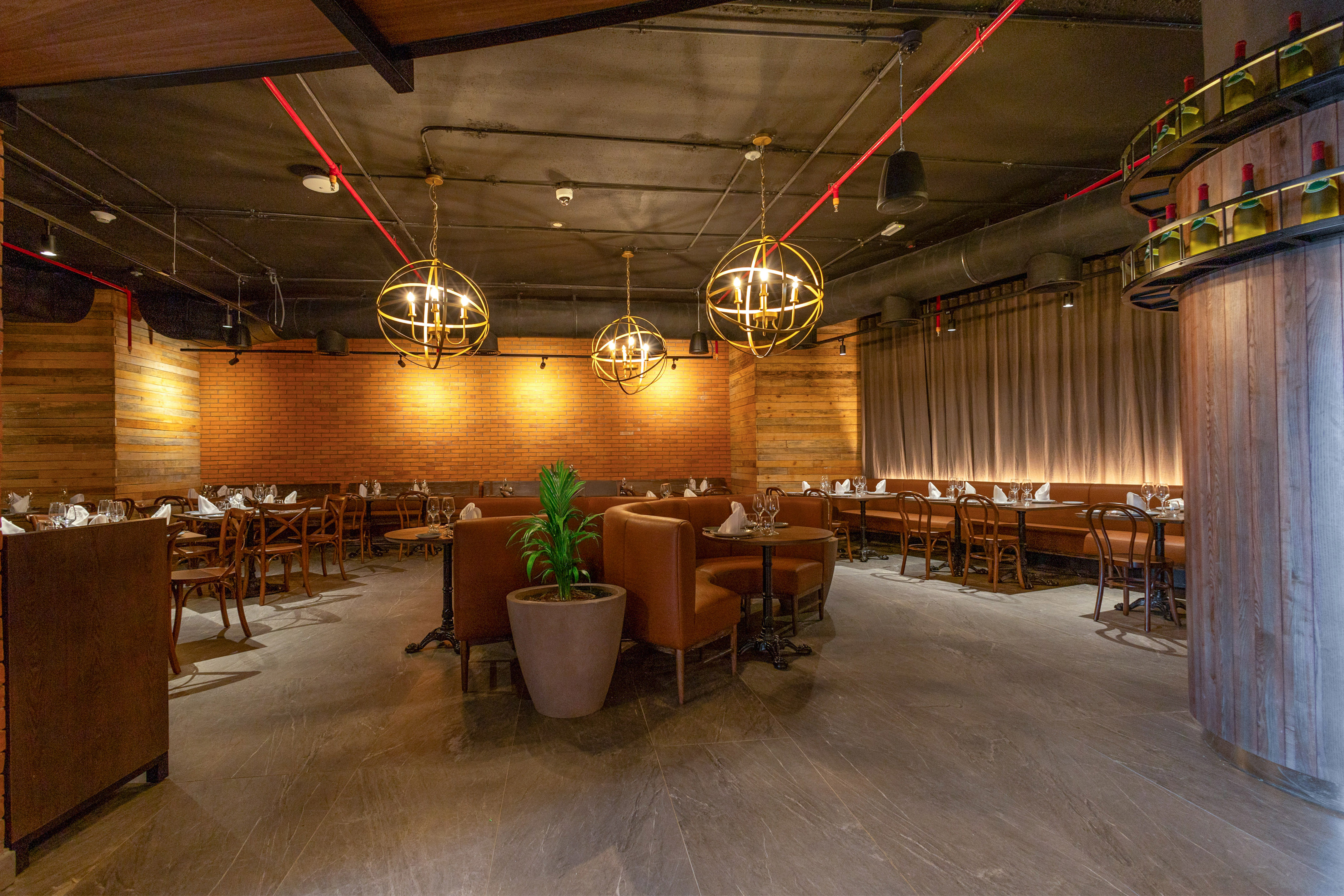 Upscale restaurant dining room with leather booths, brick walls, and gold chandeliers.