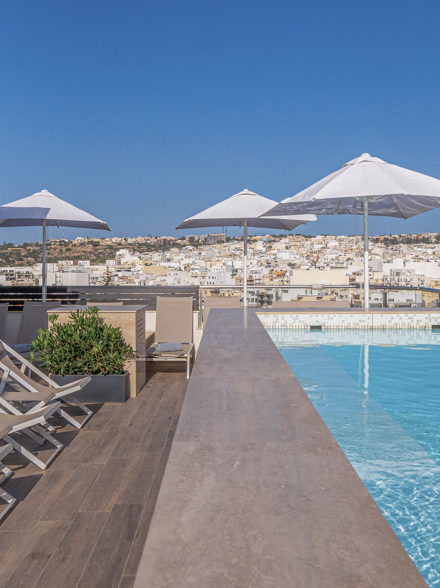 a pool with chairs and umbrellas on a rooftop