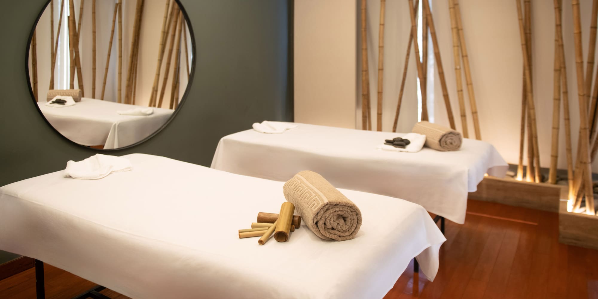 a massage table with towels and a round mirror