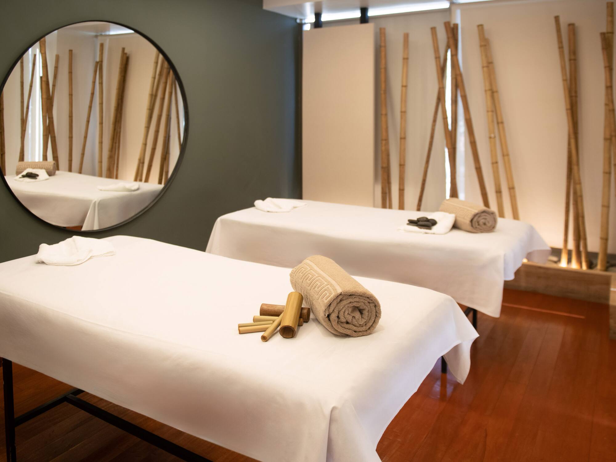 a massage table with towels and a round mirror