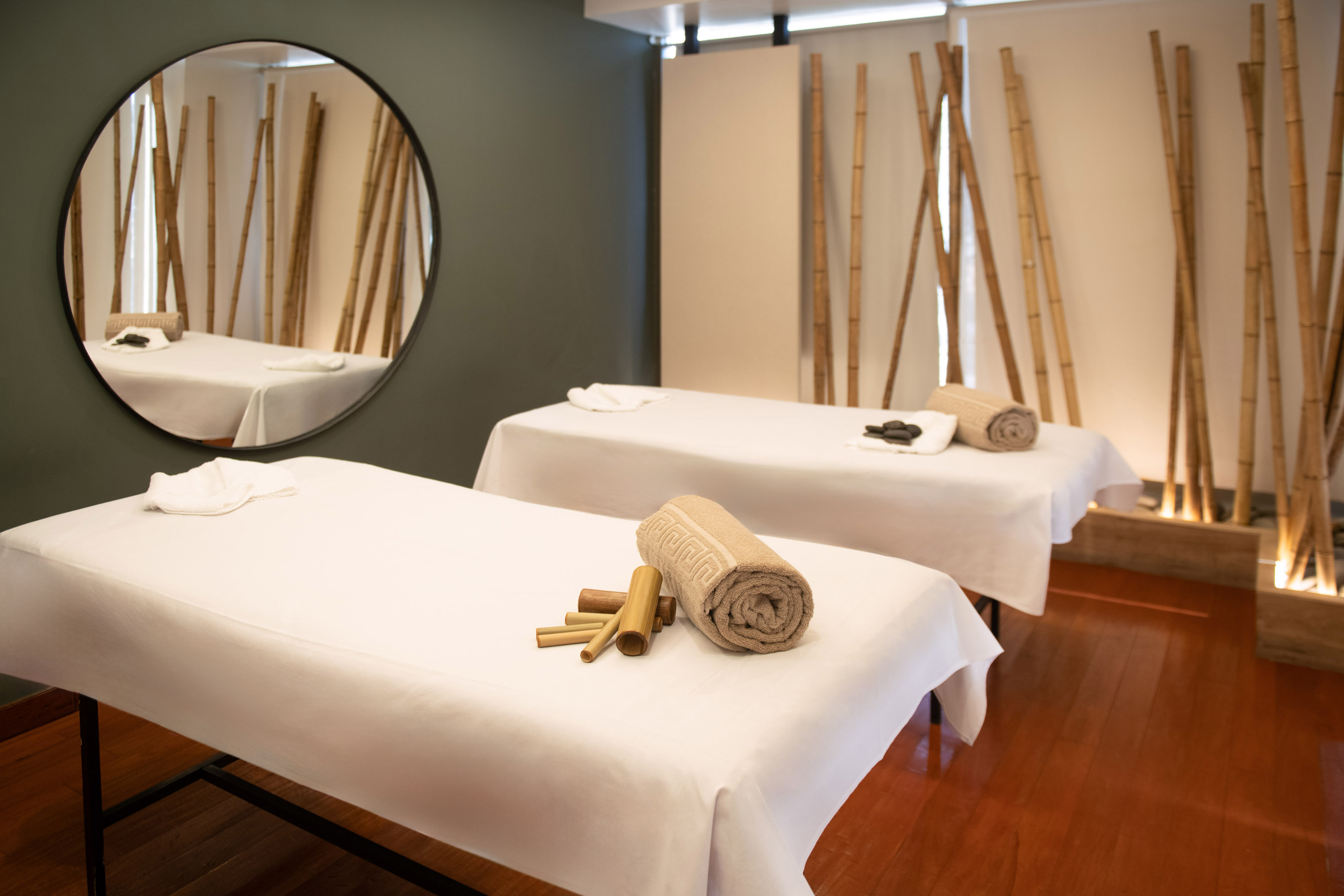 Serene spa room with two massage beds, towels, and bamboo decor.