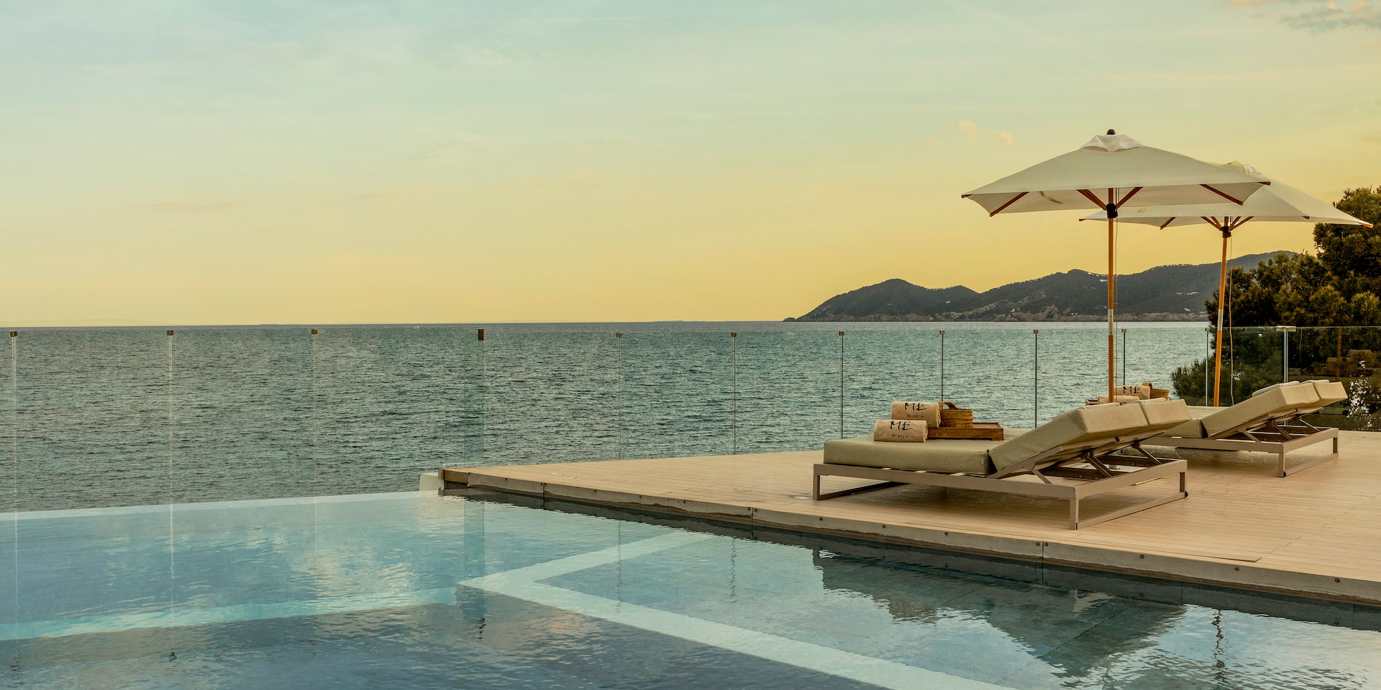a pool with a deck chair and umbrella by the water
