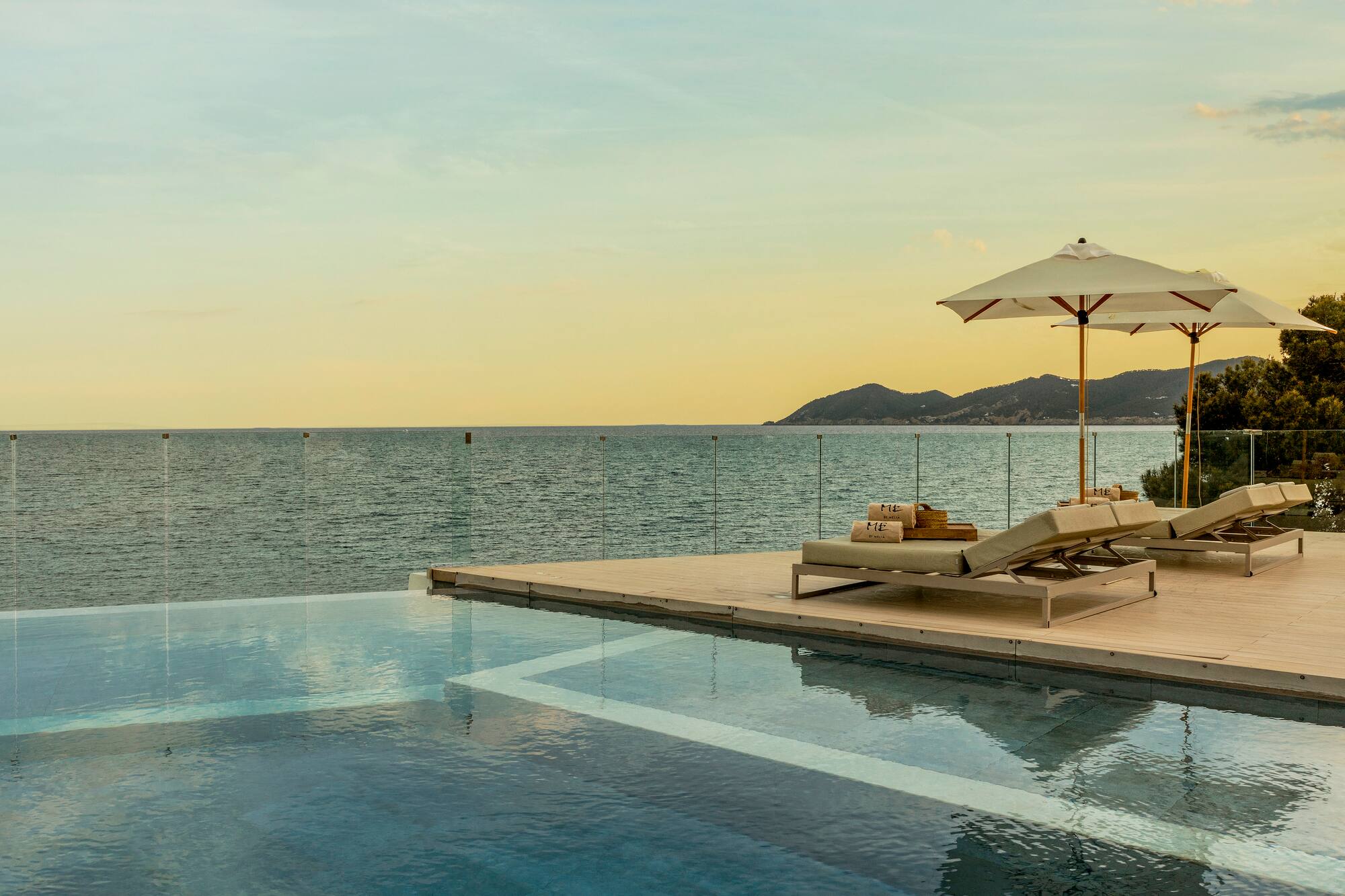 Luxury infinity pool with ocean view and lounge chairs at sunset.
