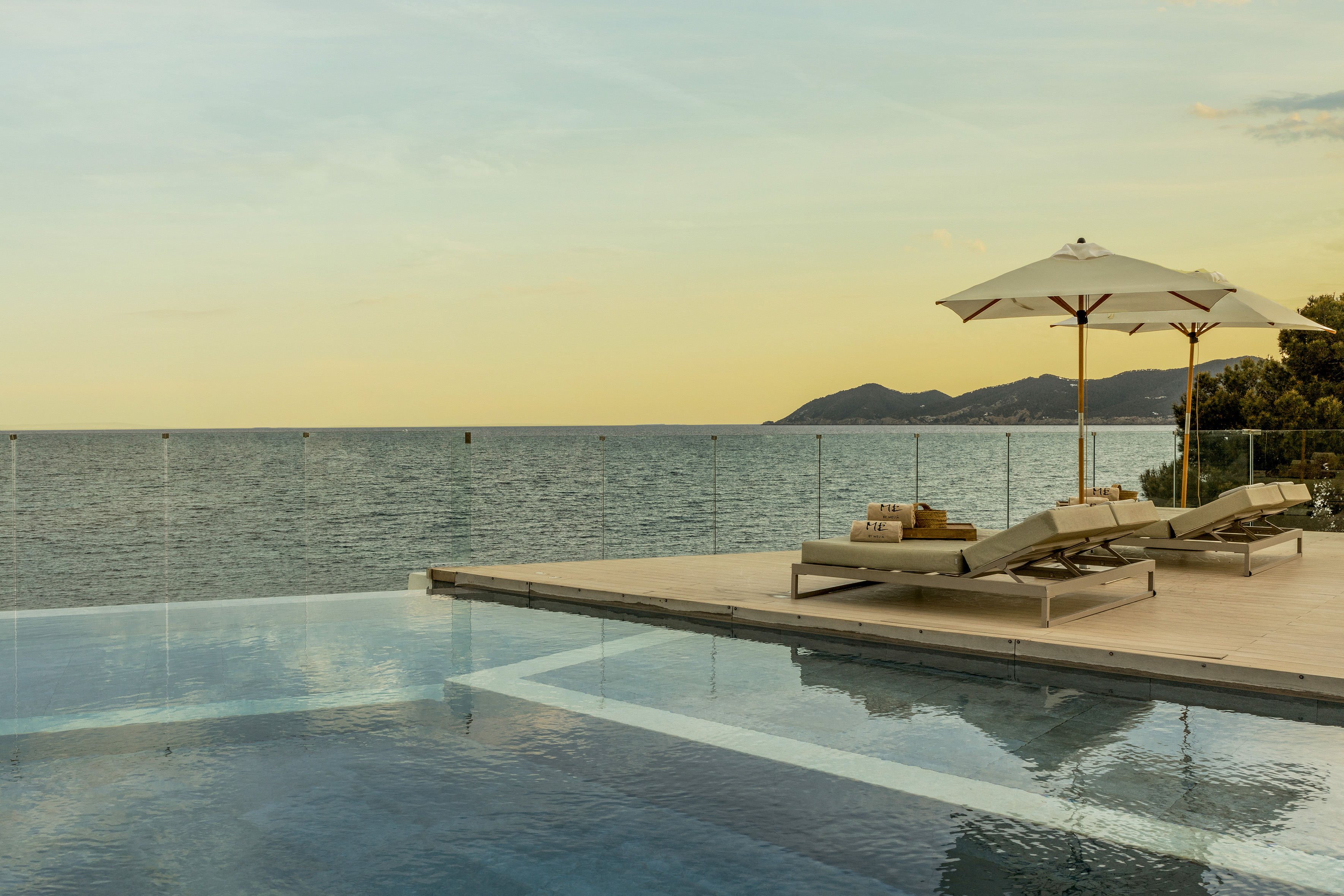 a pool with a deck chair and umbrella by the water