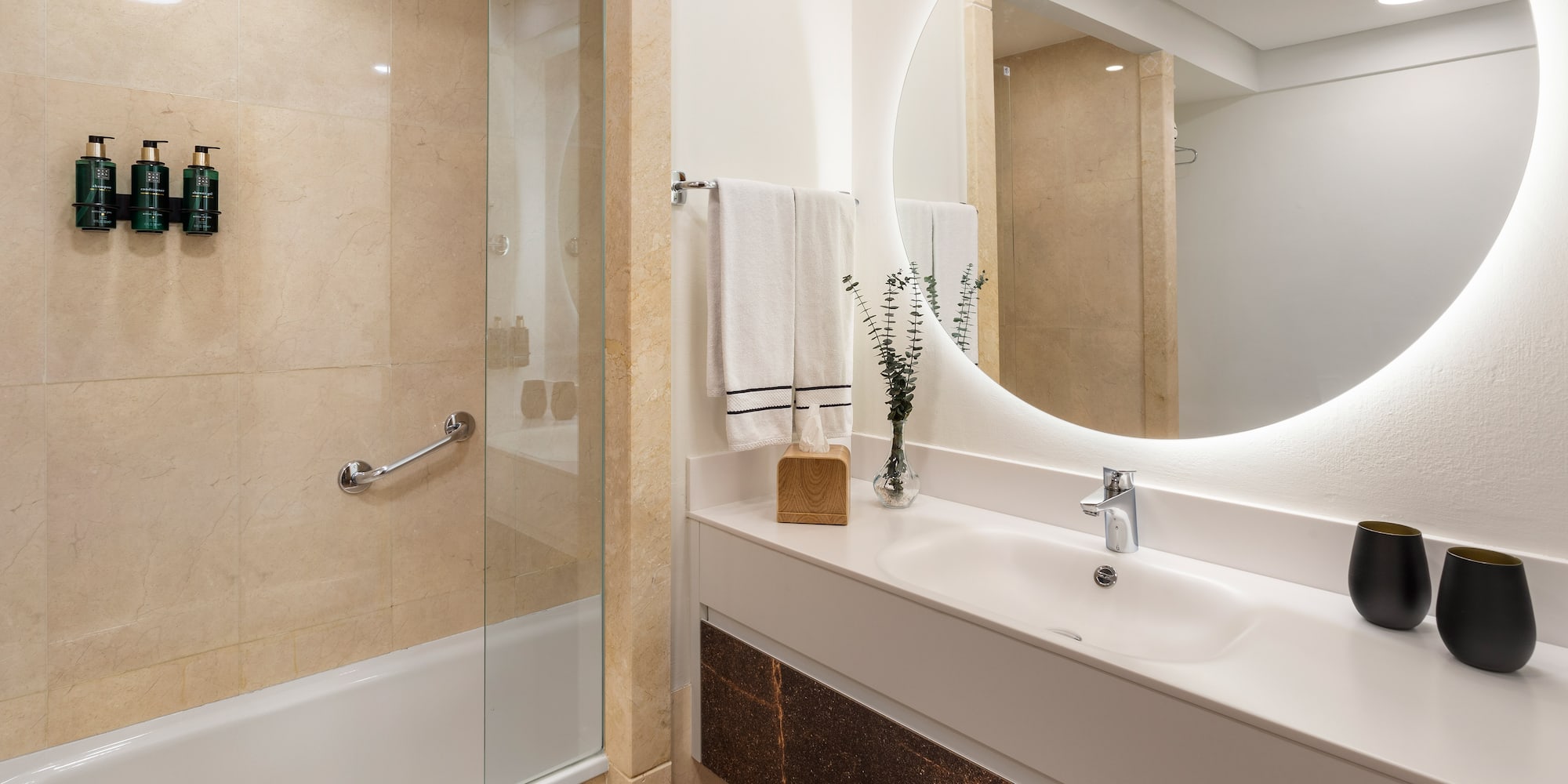 a bathroom with a round mirror and a shower