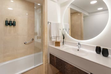 a bathroom with a round mirror and a shower