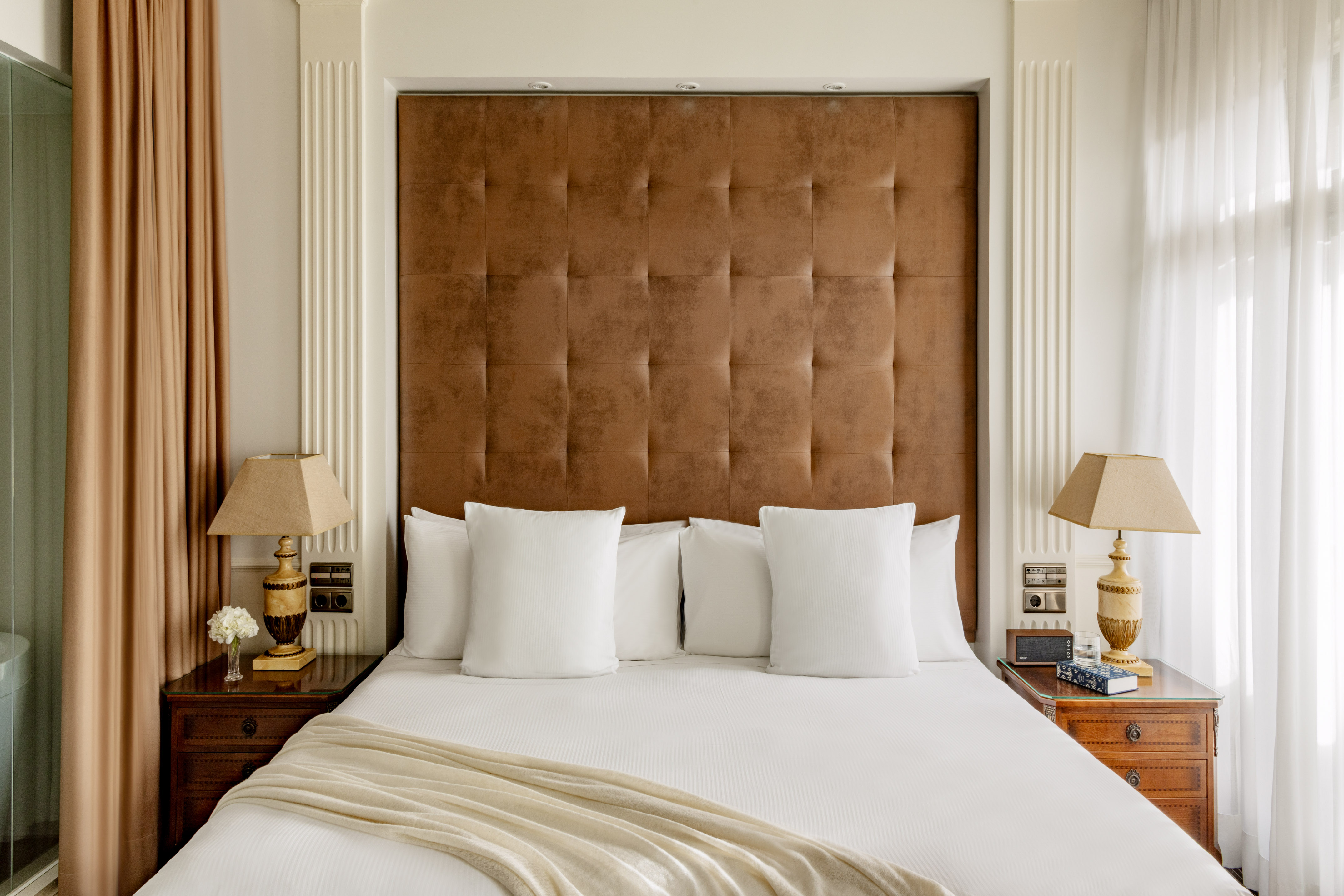 Elegant hotel bedroom with brown tufted headboard and crisp white bedding.