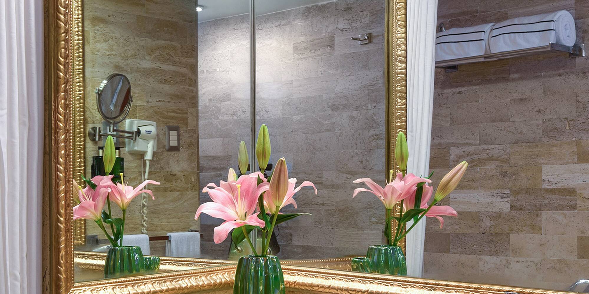 a bathroom with a mirror and flowers