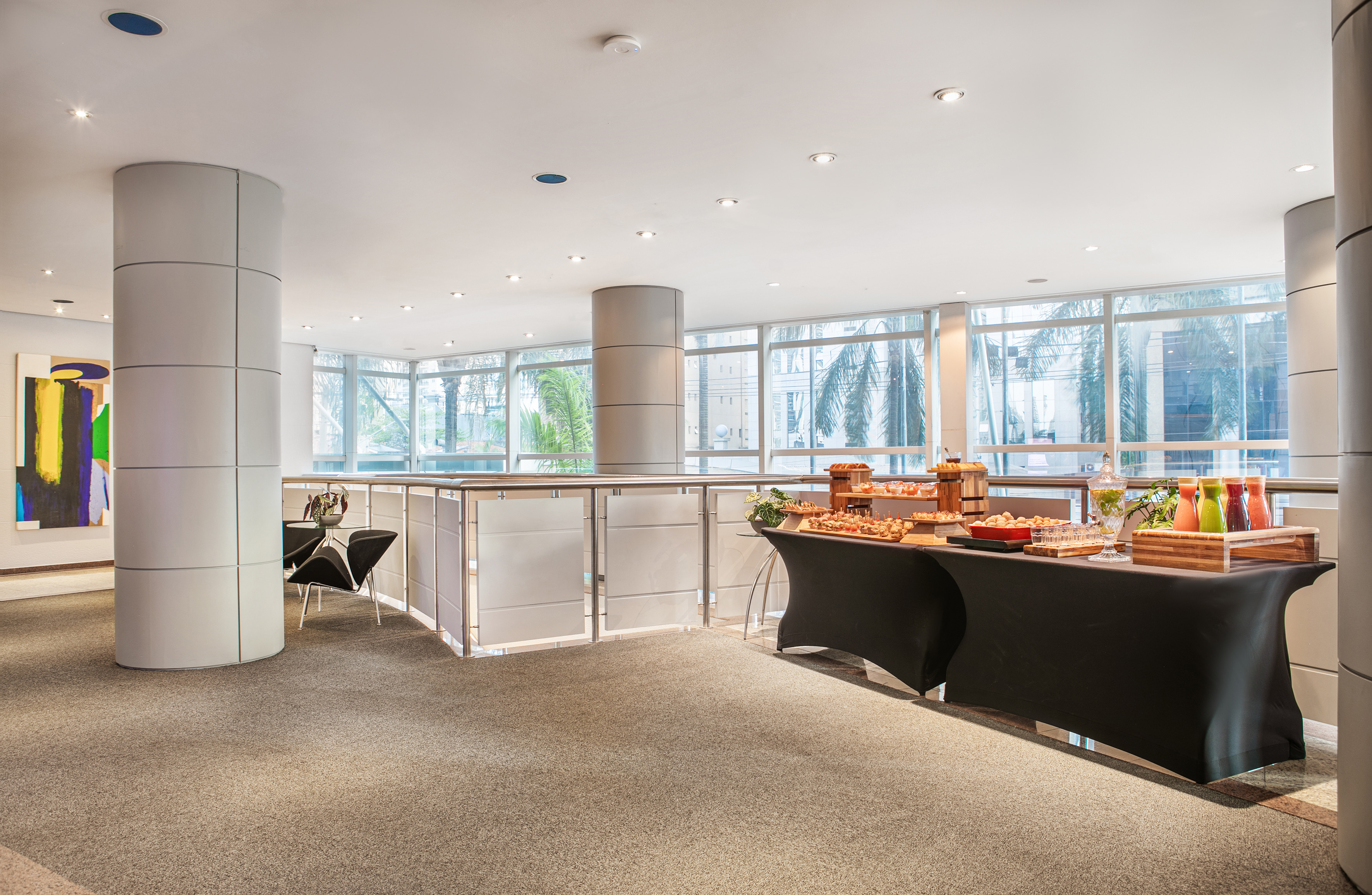 Modern lounge buffet setup with snacks, drinks, and bright windows.